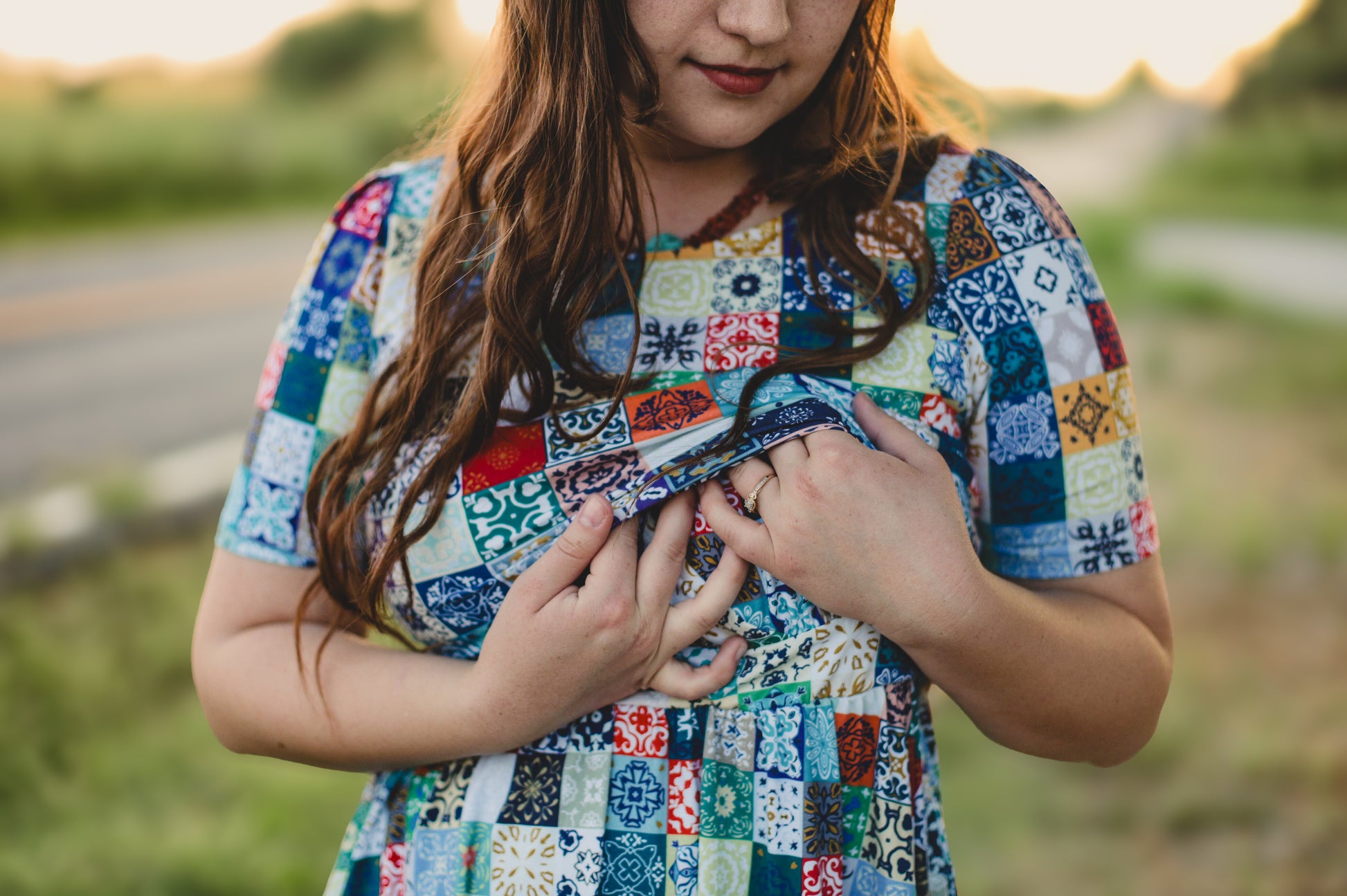 Young girl wearing a colorful patchwork modest nursing dress outdoors.