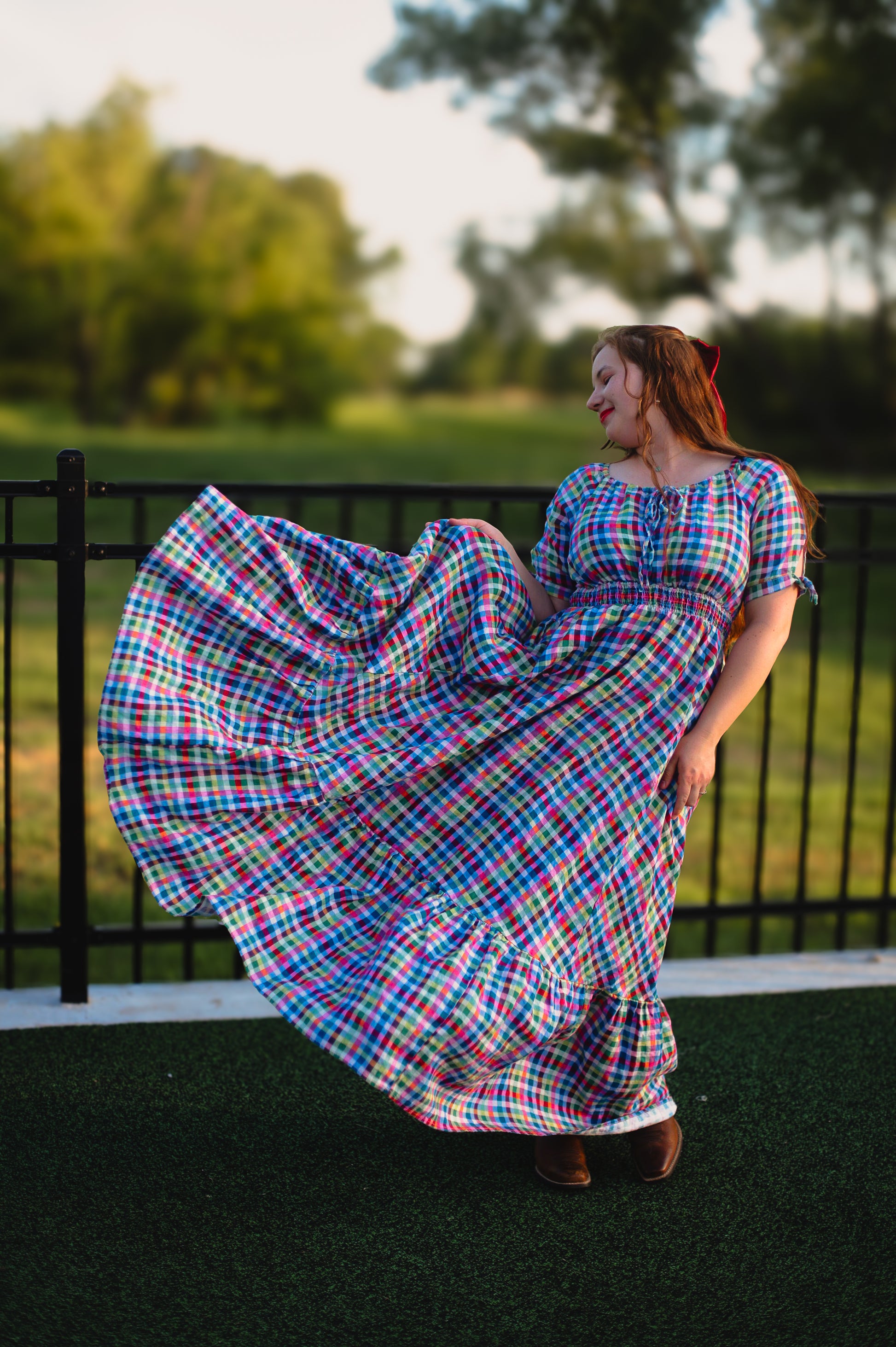 Woman in a colorful plaid modest nursing dress standing outdoors with trees in the background