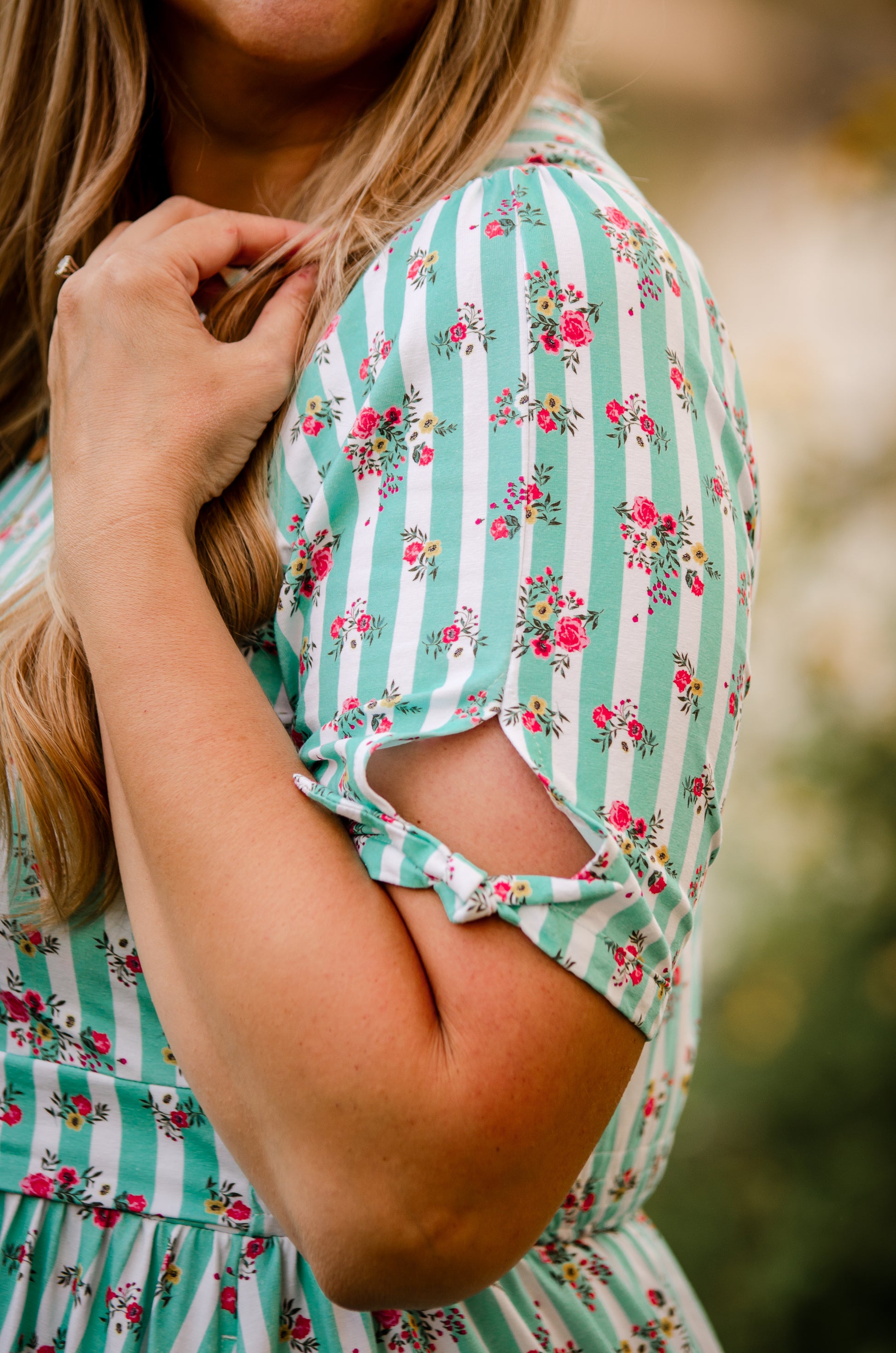 Woman wearing a green and white striped modest nursing dress with floral patterns.