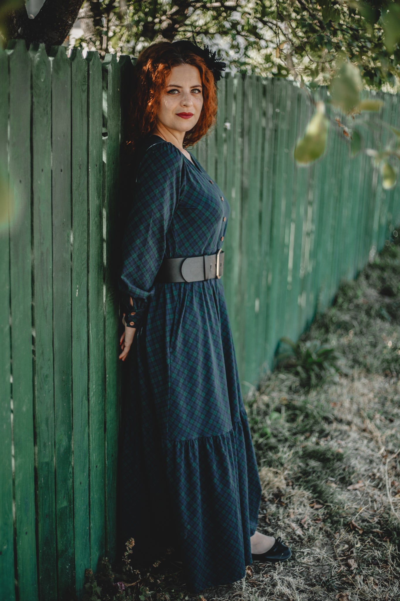Woman in modest nursing blue dress by fence