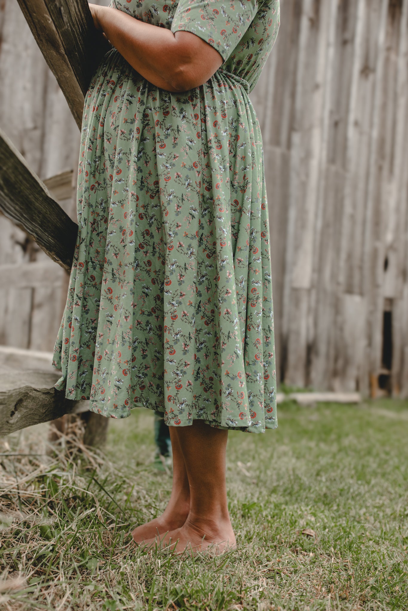 Woman in modest nursing floral dress by fence