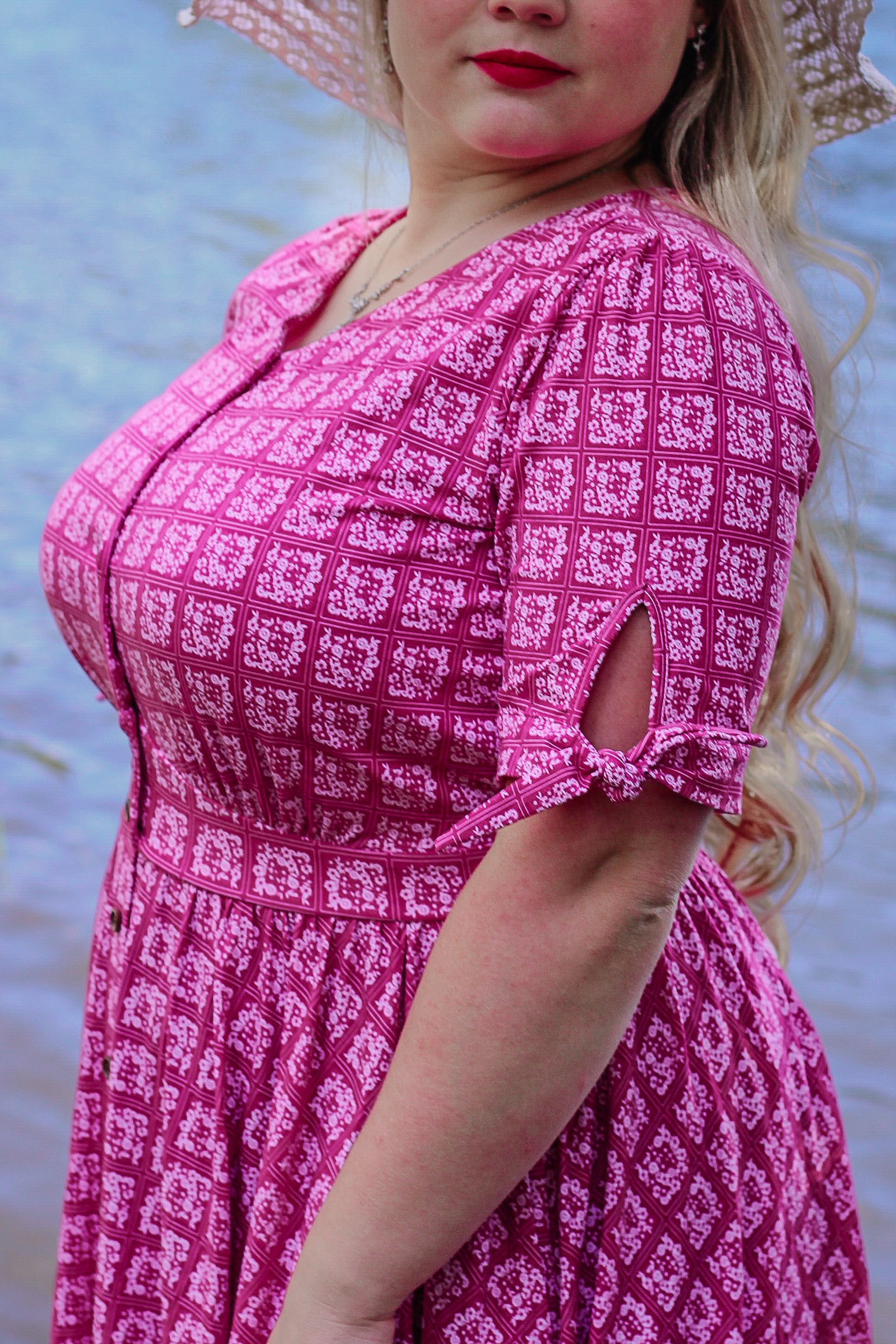 Woman wearing a pink patterned modest nursing dress with a blurred natural background