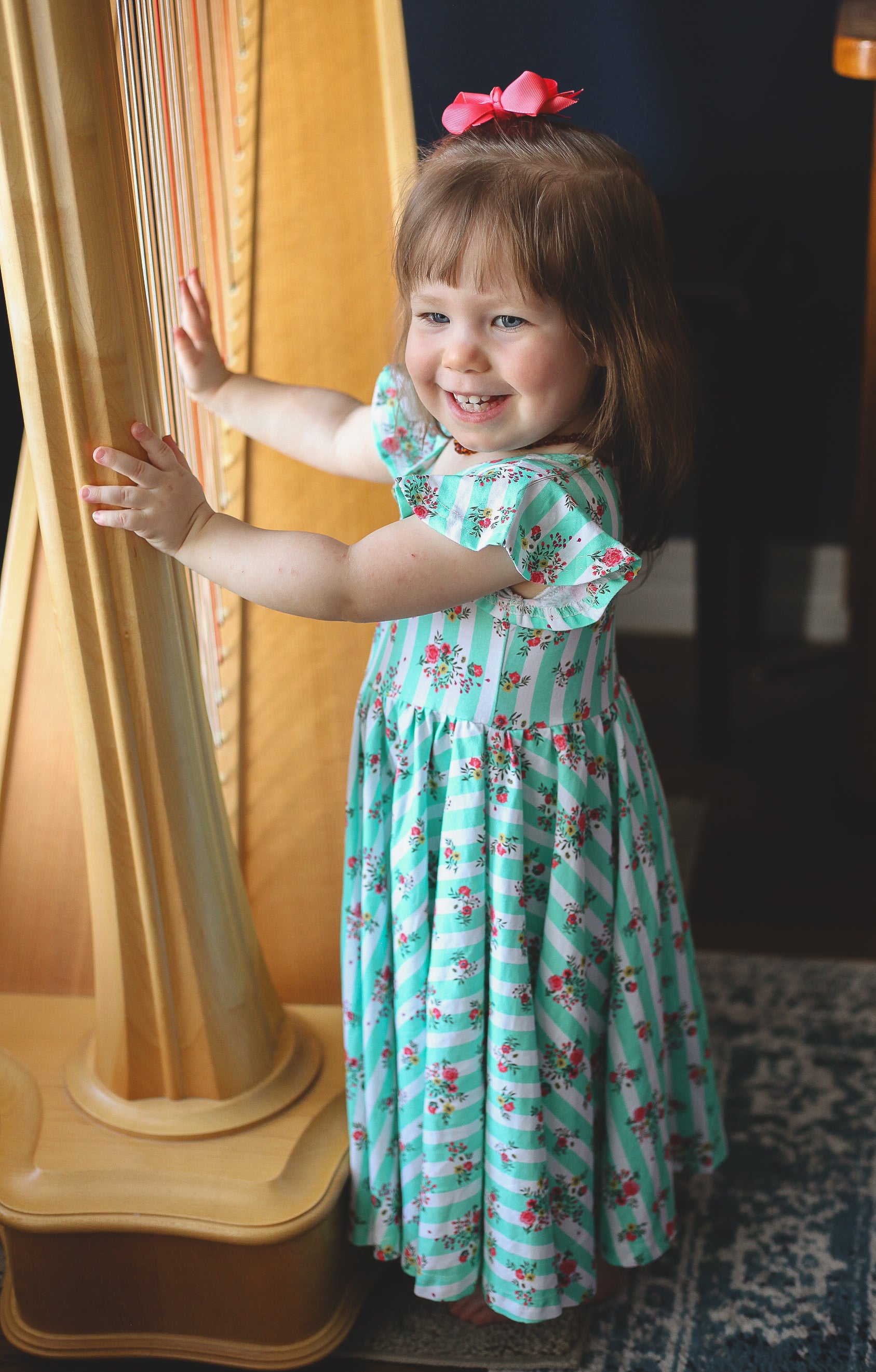 Young girl in a floral modest dress standing next to a curtain