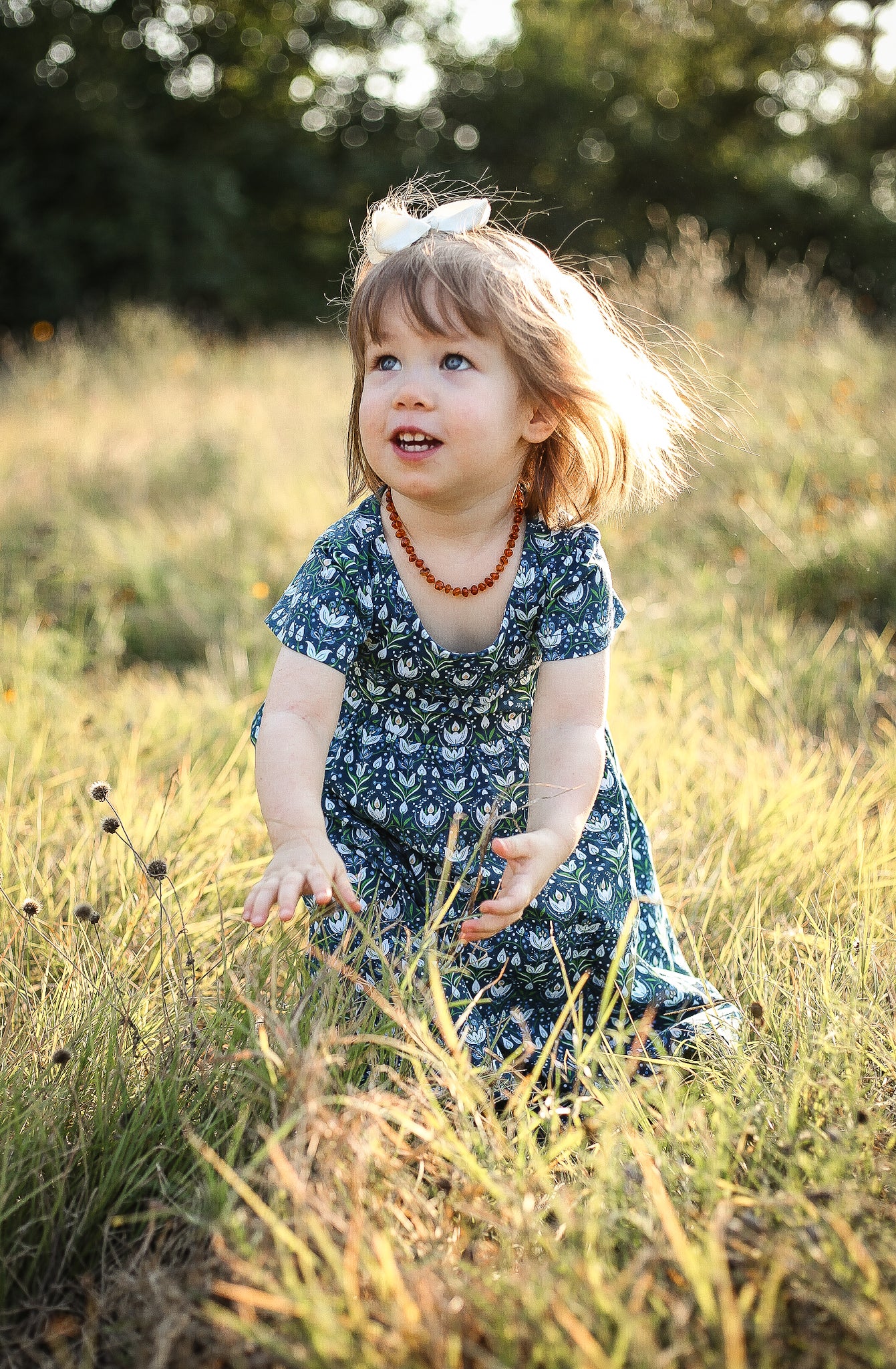 Child sitting in blue floral dress in grass