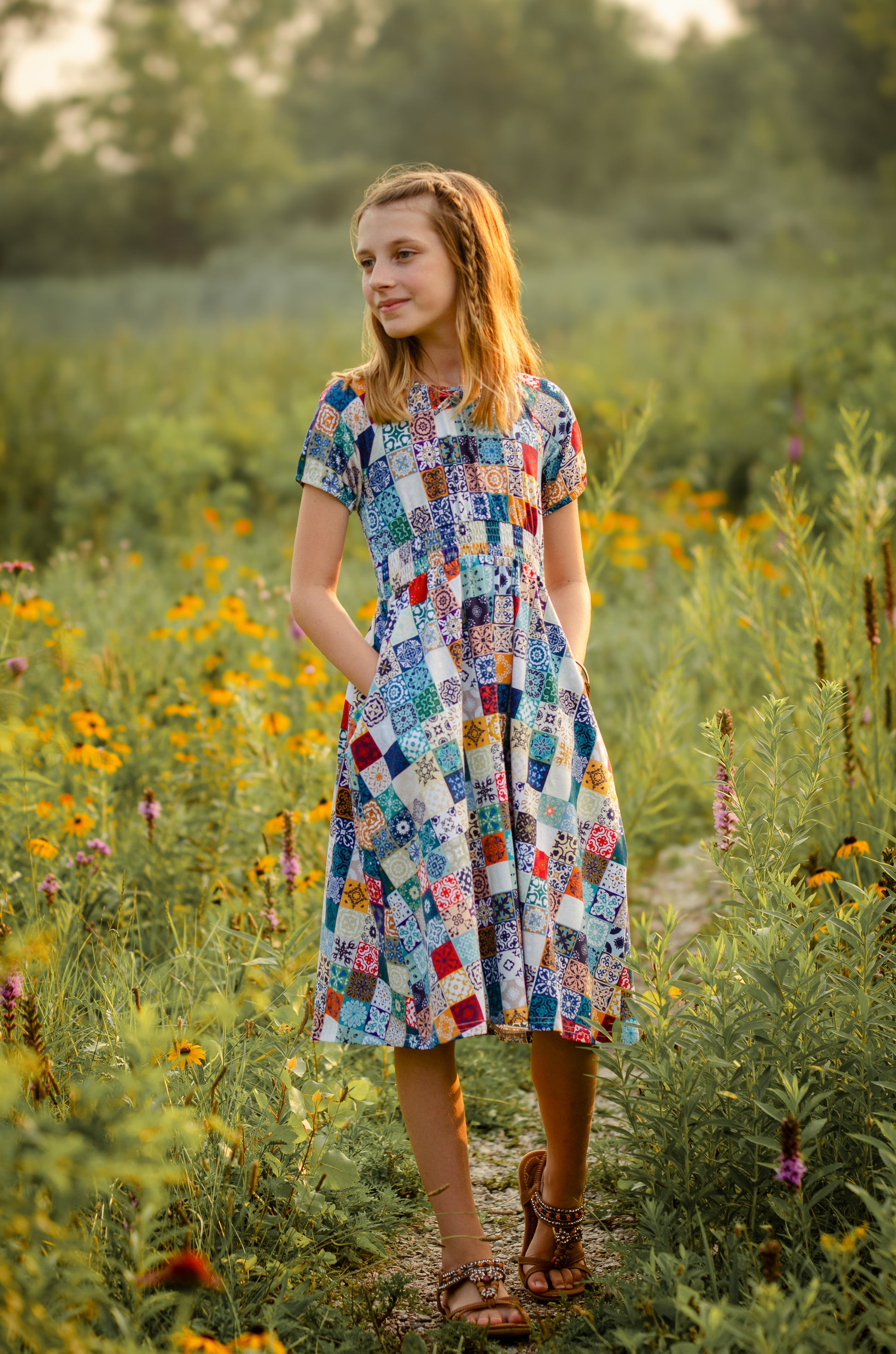 Woman in a colorful patchwork modest dress standing in a field of wildflowers