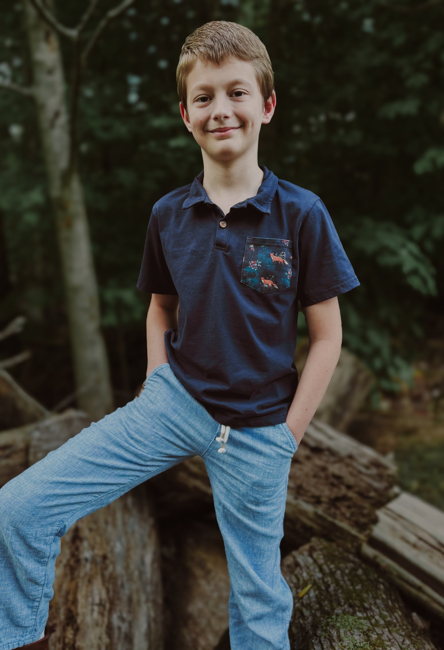 Boy wearing blue polo and jeans outdoors.