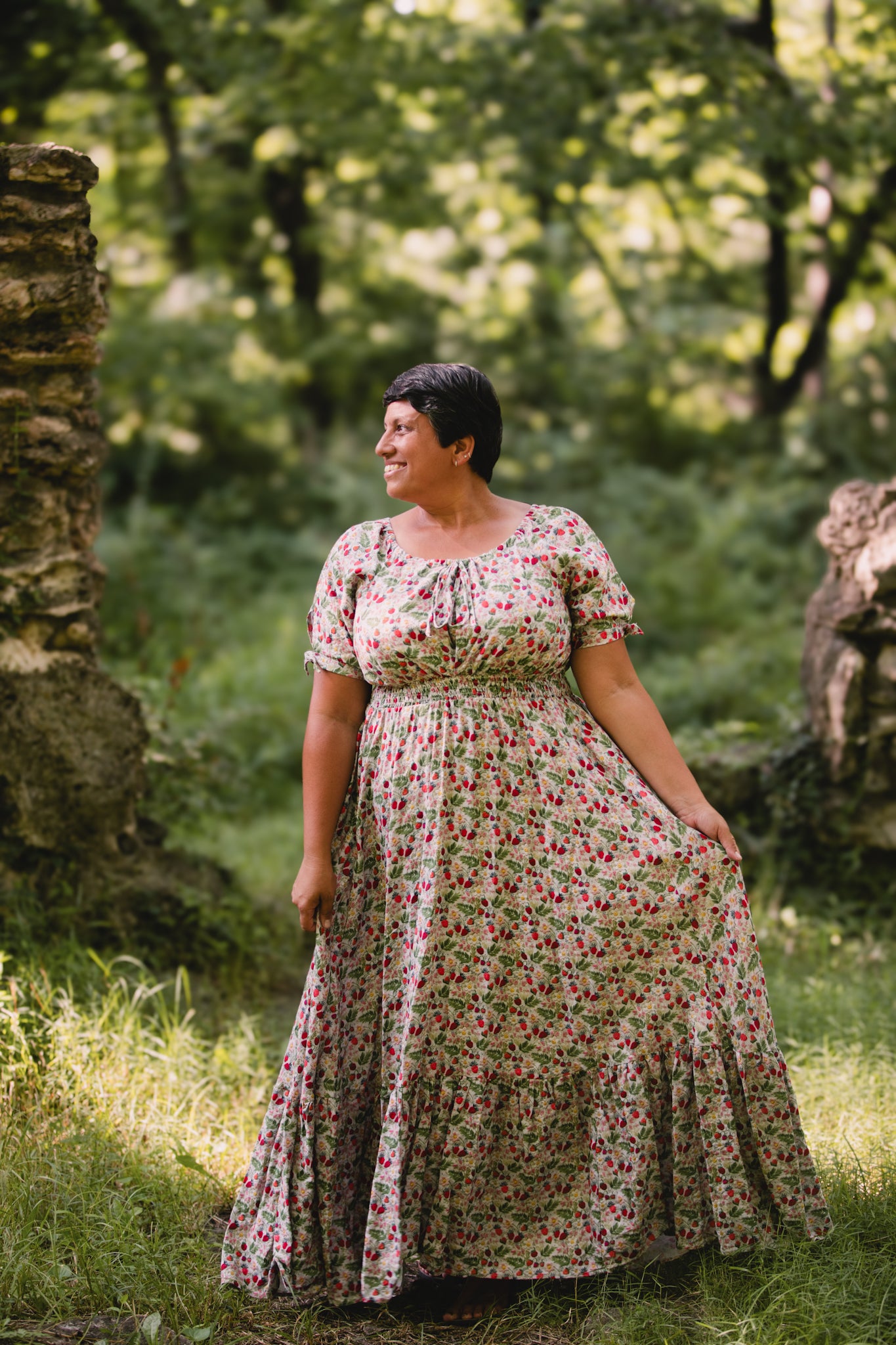 Woman in a floral modest nursing dress standing in a natural setting with greenery.
