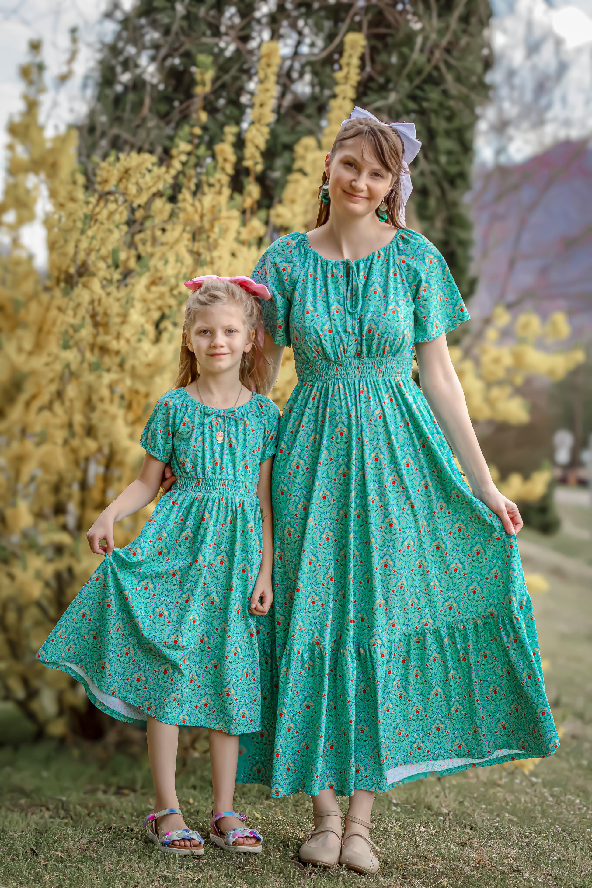 Young girl wearing a modest green dress with her mother in a modest green nursing dress