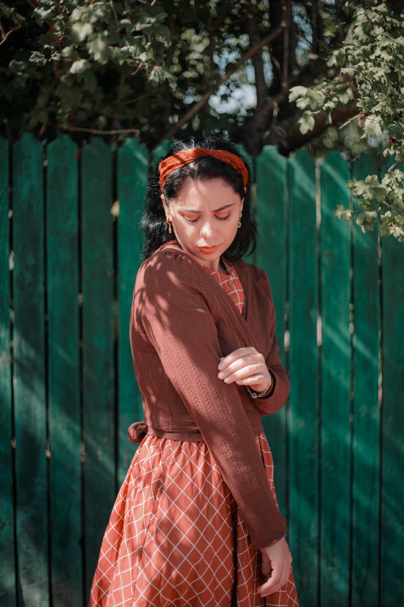 Woman in modest nursing brown dress coat fence