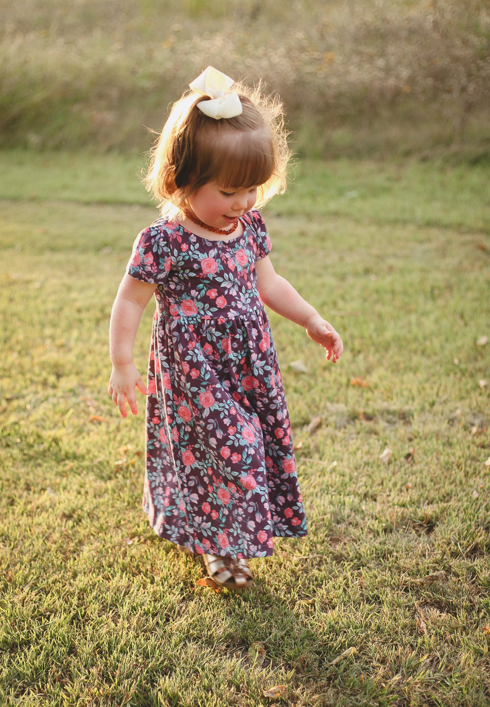 Child in floral dress standing on grass