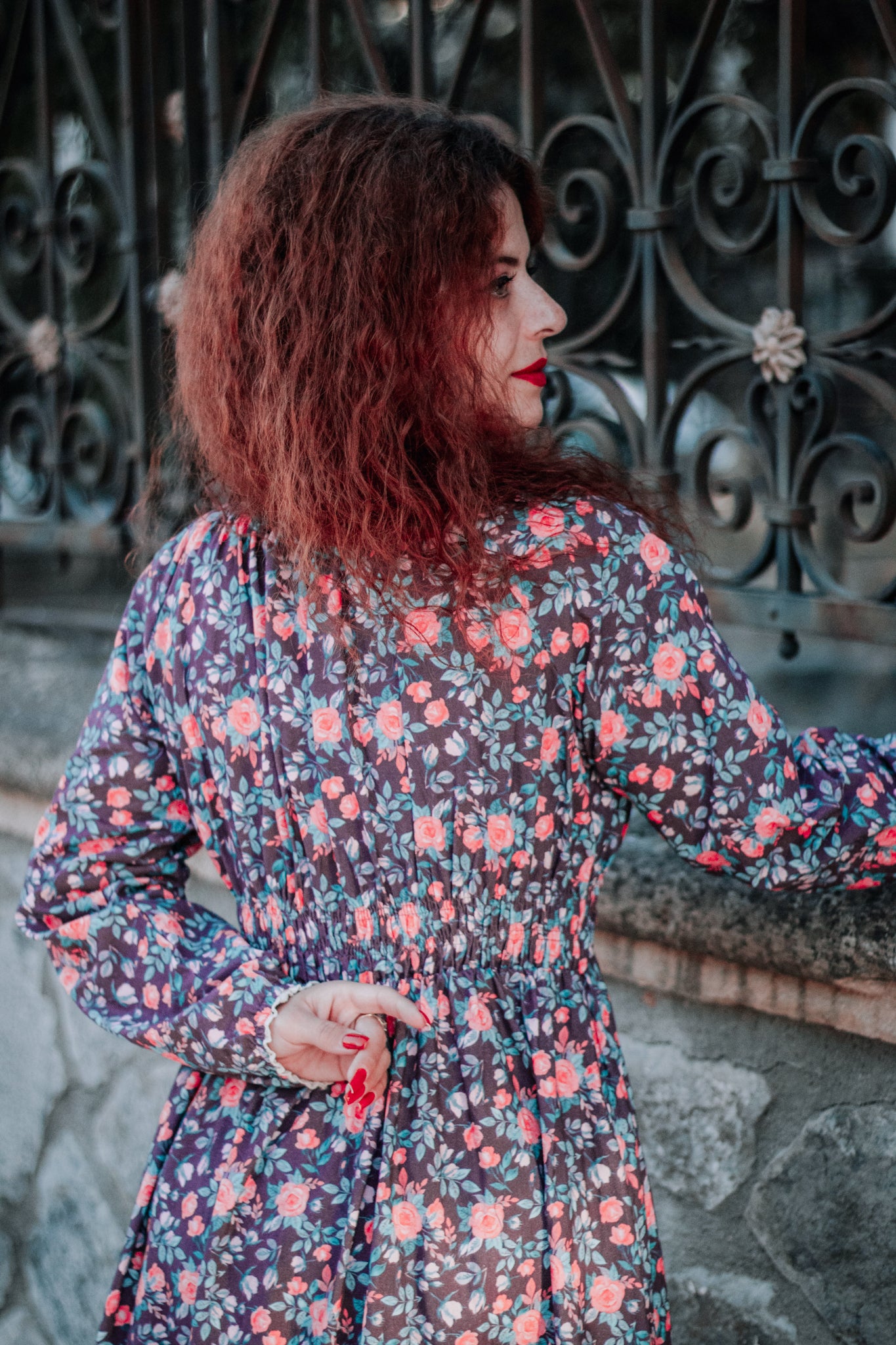 Woman in modest nursing floral dress by gate