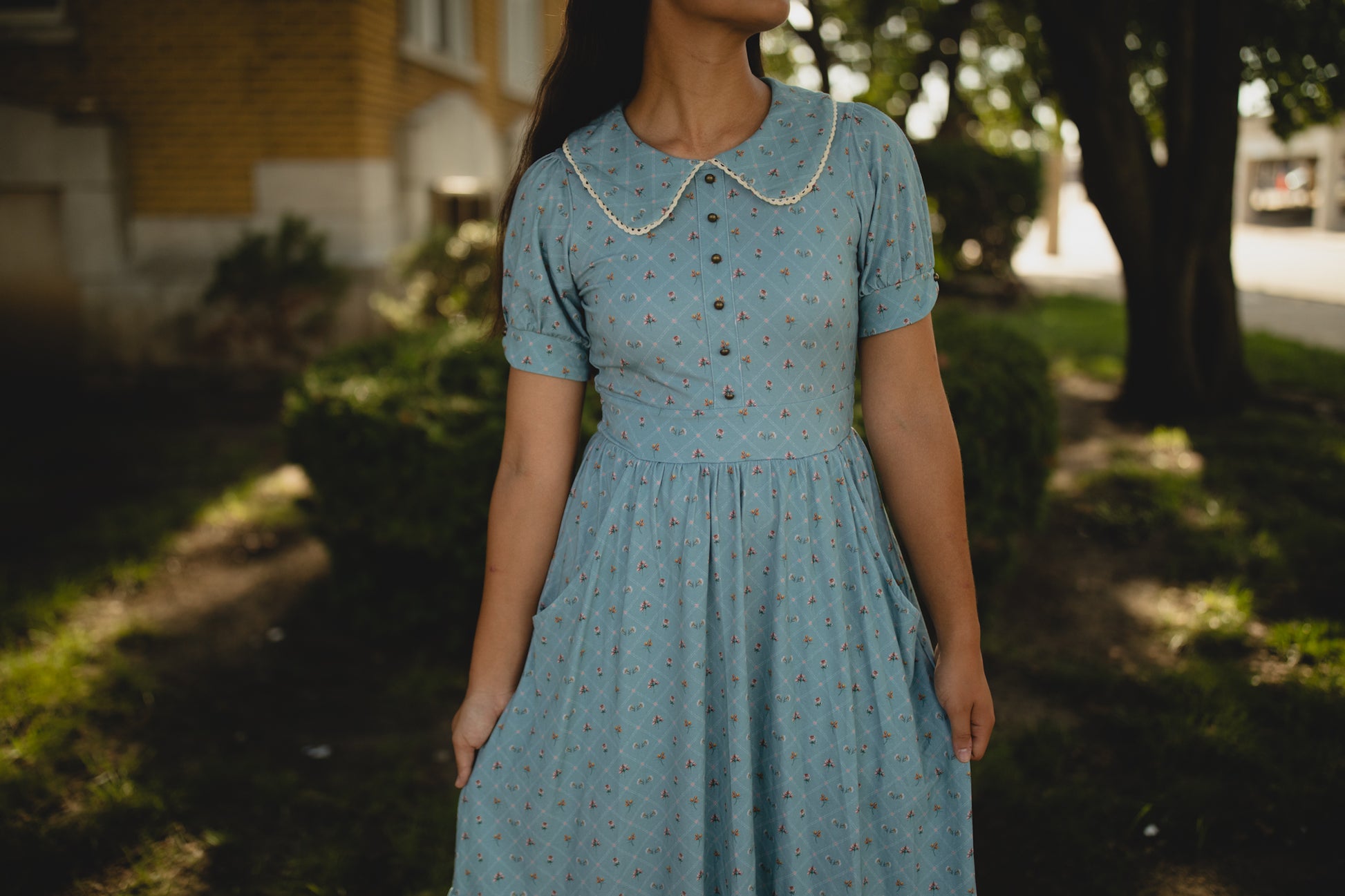 Woman wearing a blue modest nursing dress with a pattern in an outdoor setting