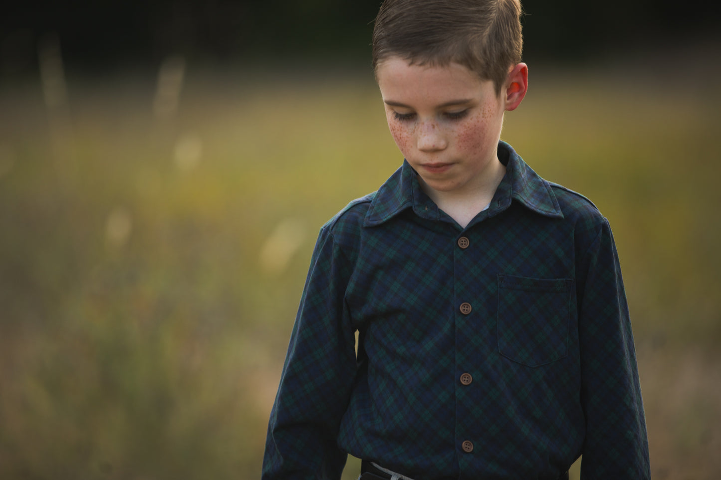 Boy in green plaid shirt outdoors