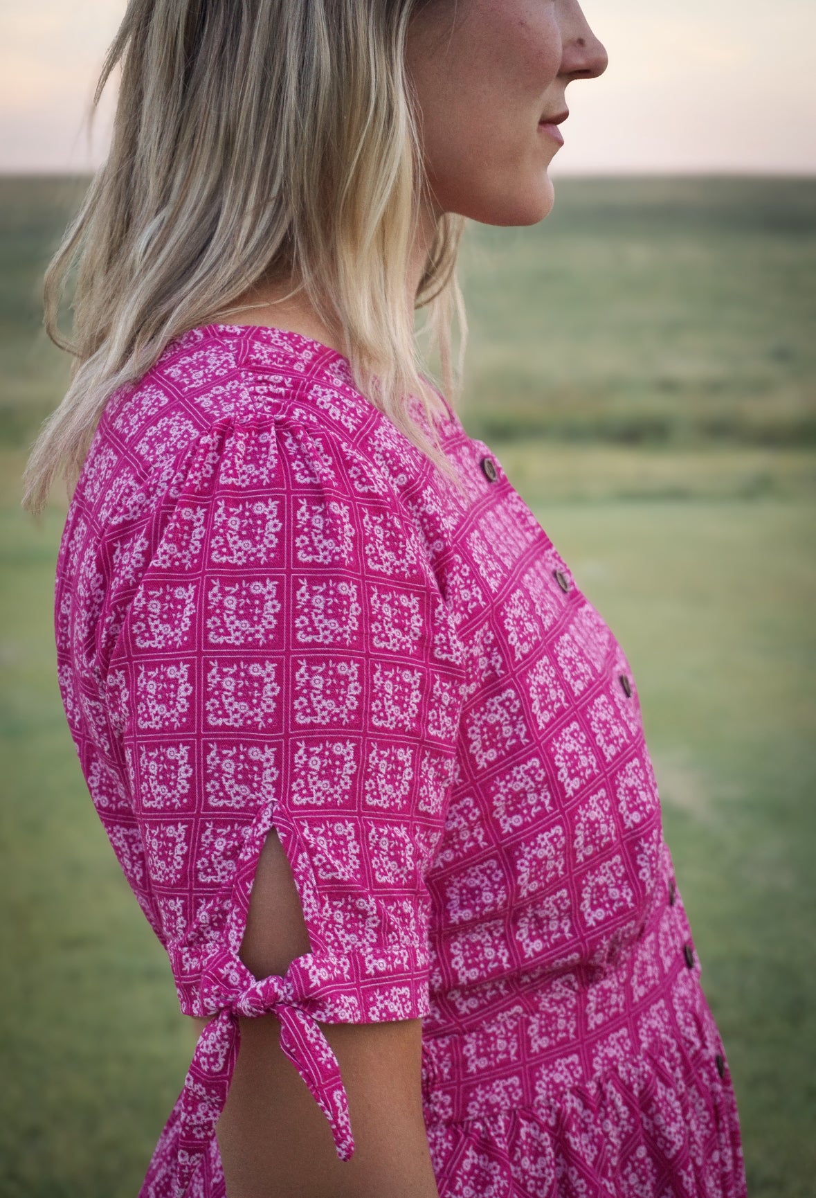 Woman wearing a pink patterned modest nursing dress standing in a field.