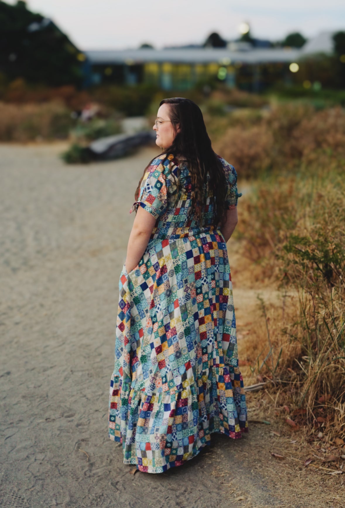Woman in a colorful modest nursing dress standing on a path with blurred background