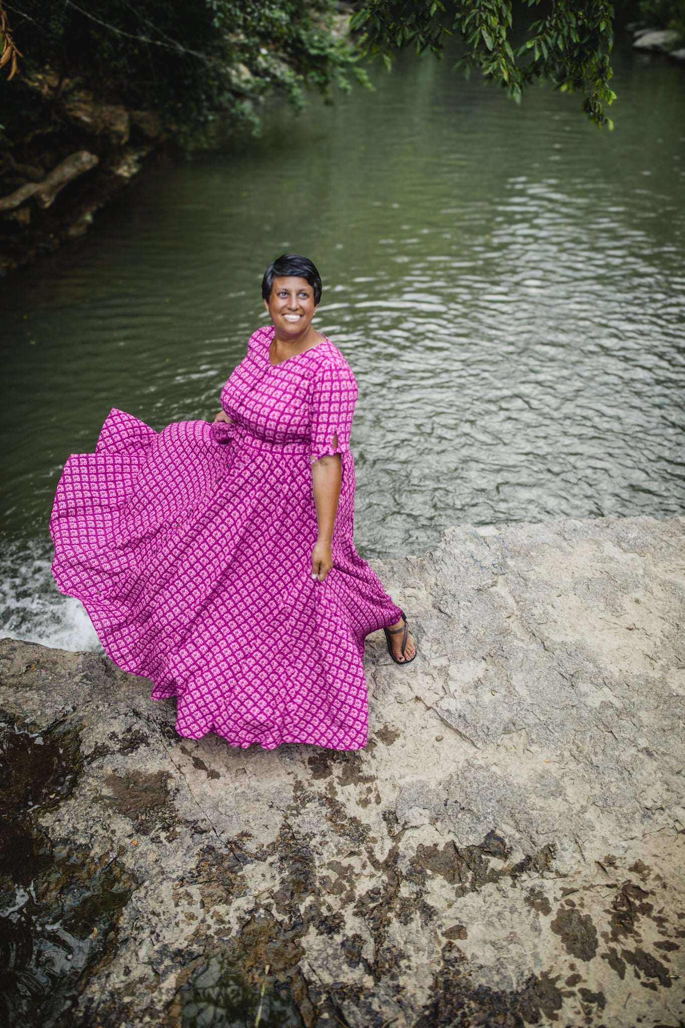 Woman in a pink modest nursing dress standing by a body of water
