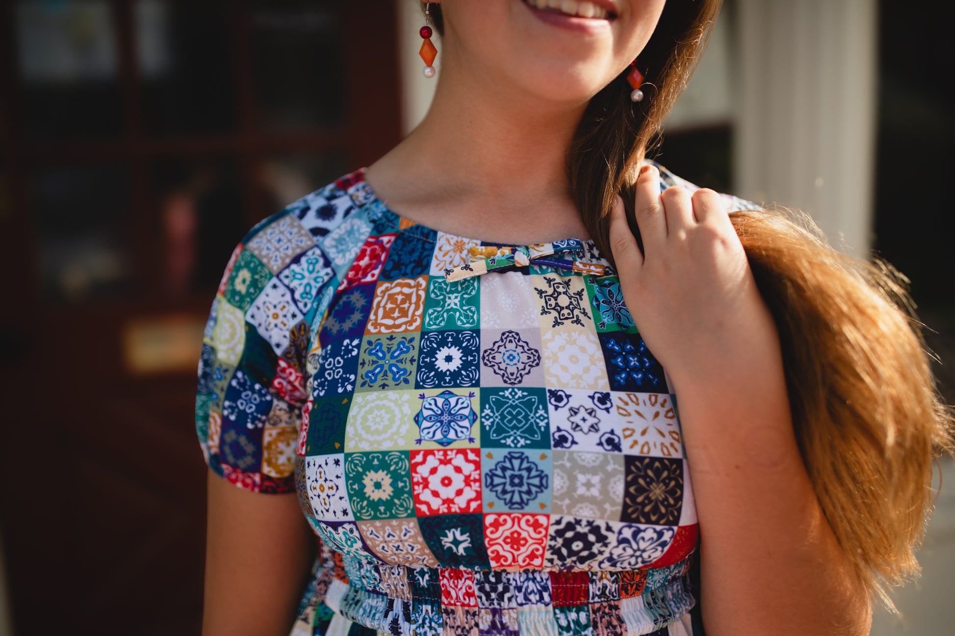 Woman wearing a colorful patchwork modest nursing dress with a blurred background