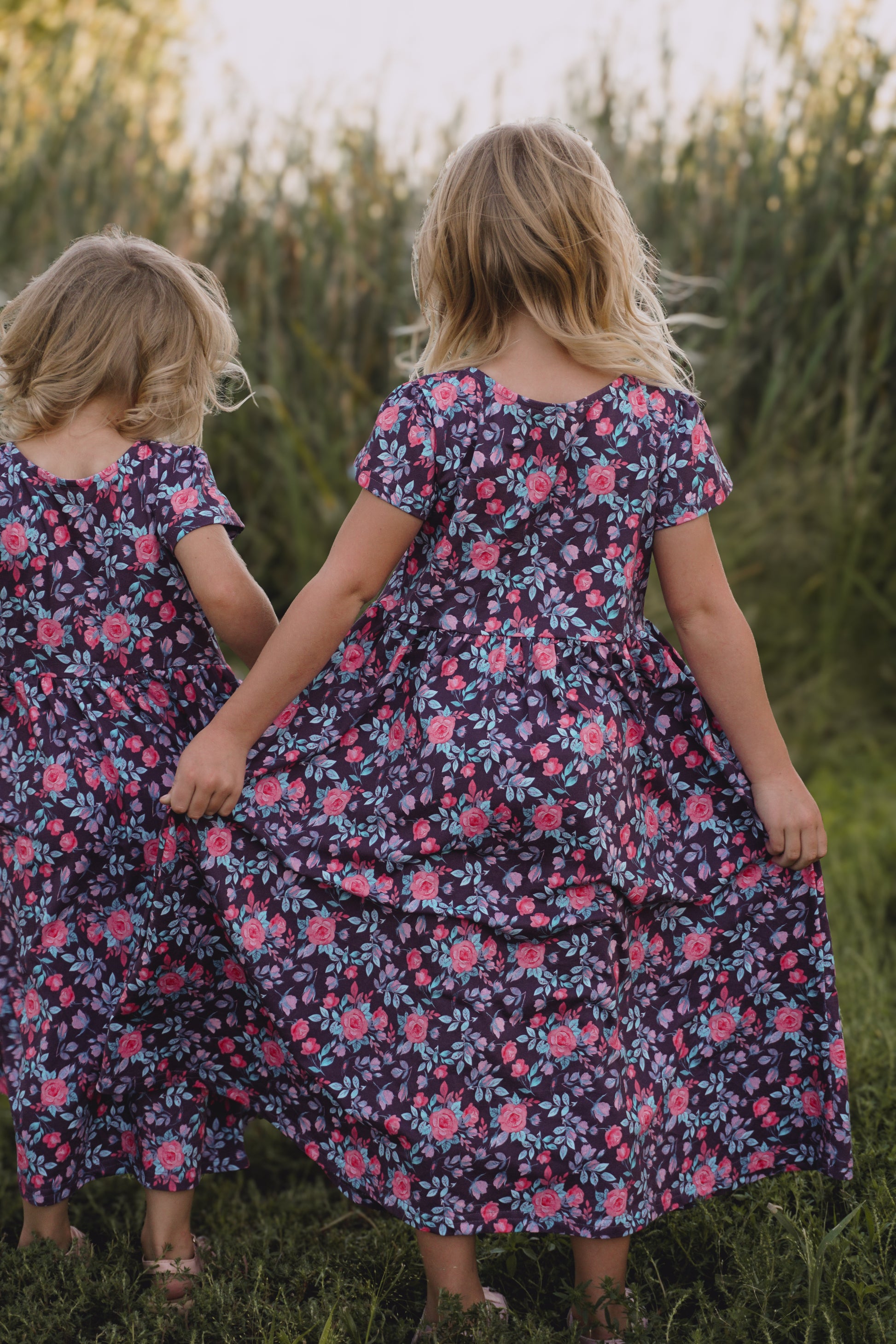 Two children in floral dresses standing in field