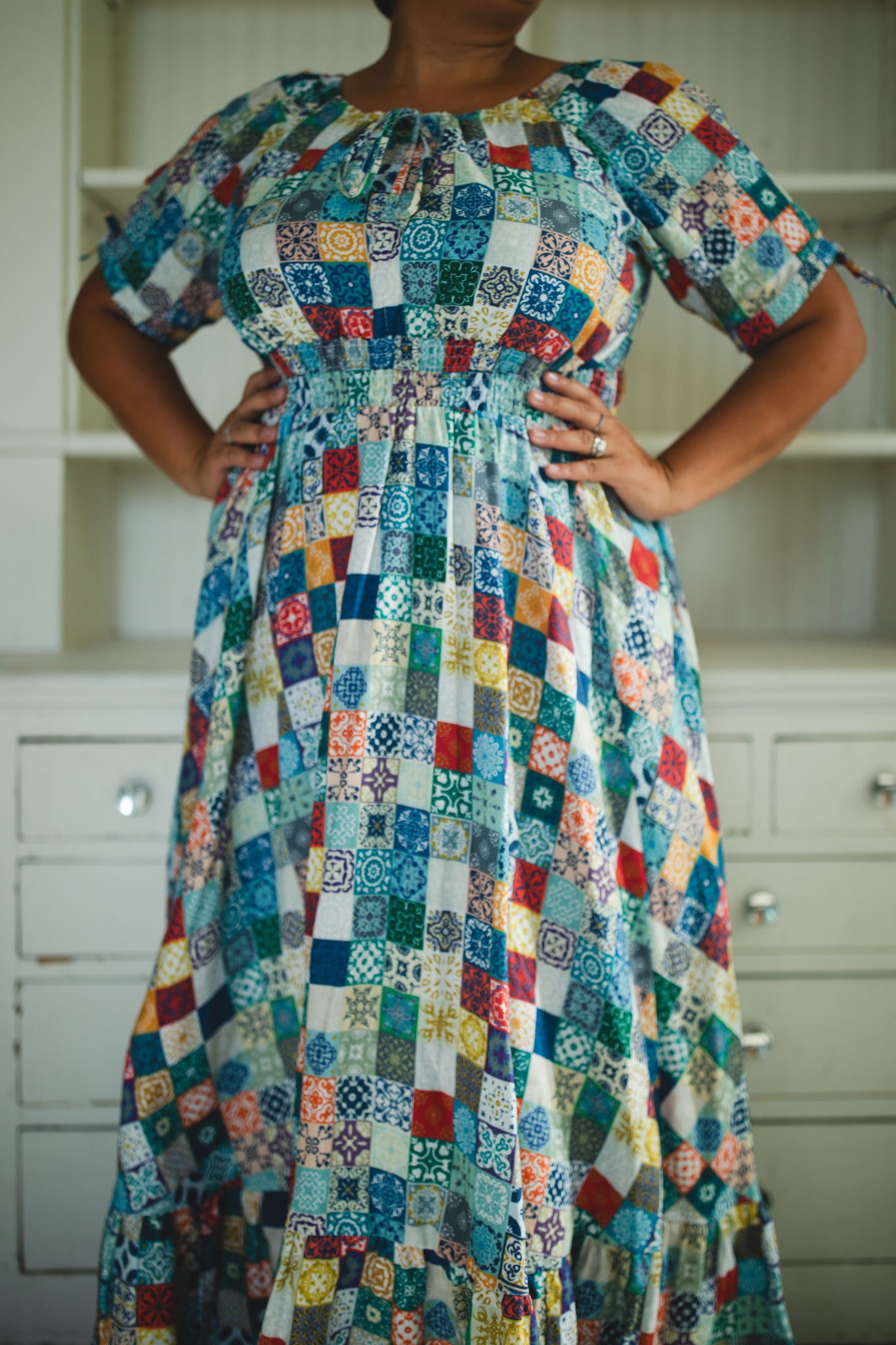 Multicolored patterned modest nursing dress worn by a person in a kitchen setting