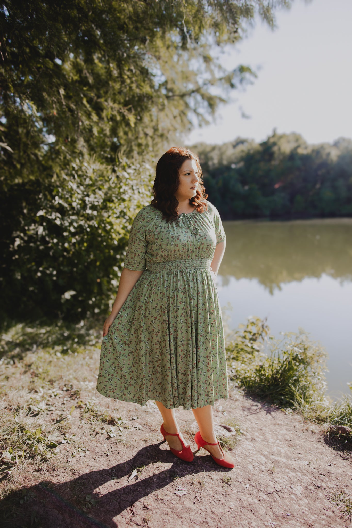 Woman in modest nursing green dress standing by lake