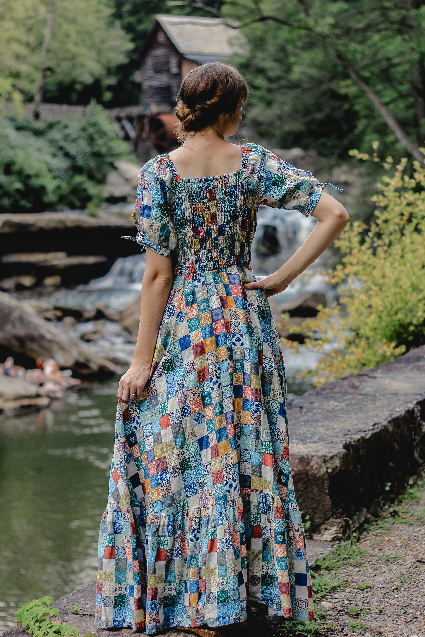 Woman in a colorful modest nursing dress standing by a river with a scenic background