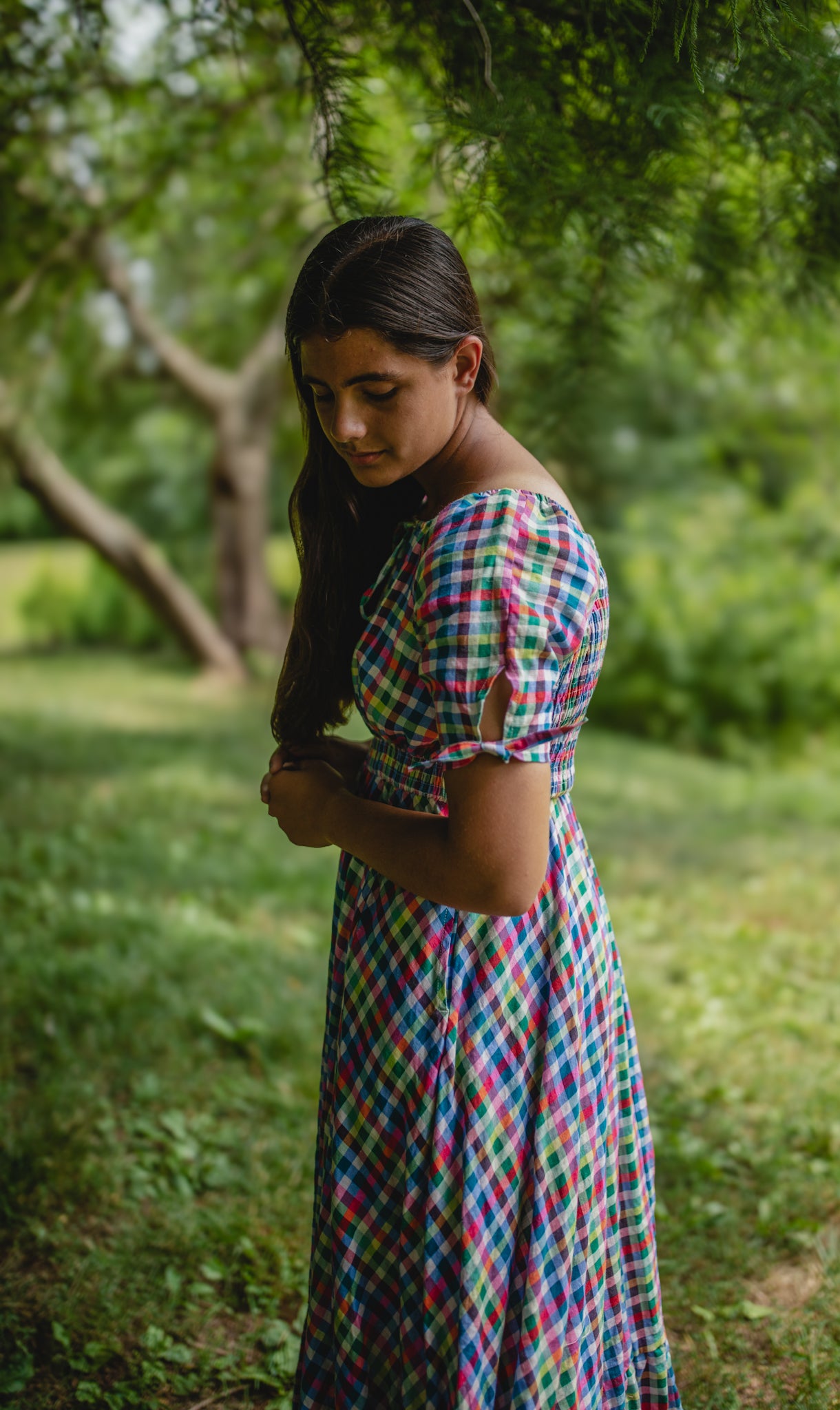 Woman in a colorful modest nursing dress standing in a green, natural setting