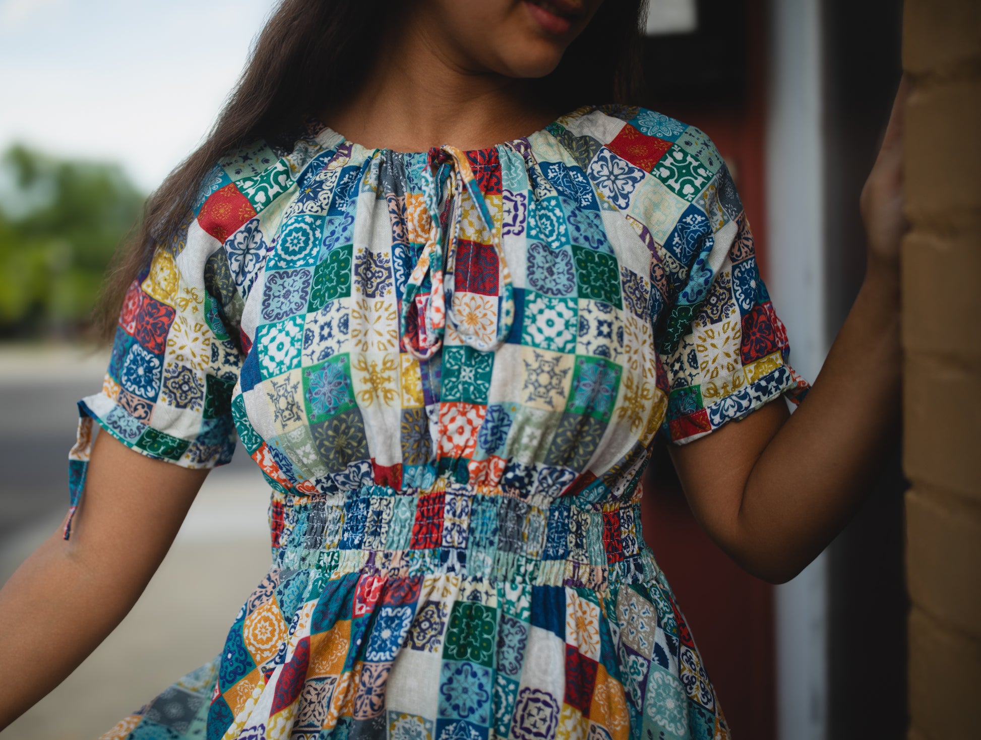 Multicolored patchwork modest nursing dress worn by a person with a blurred background