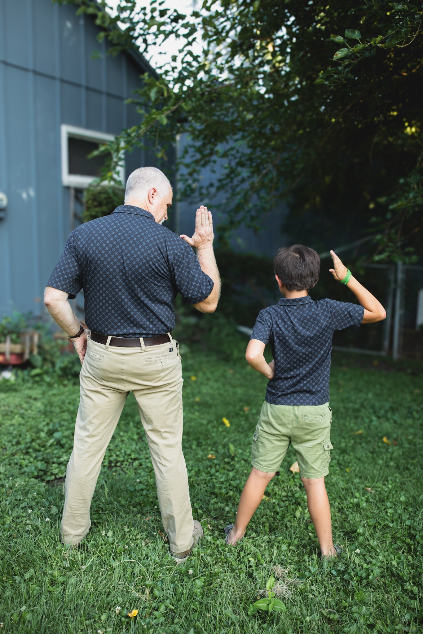Young boy wearing a dark blue polo shirt with his father in a matching shirt