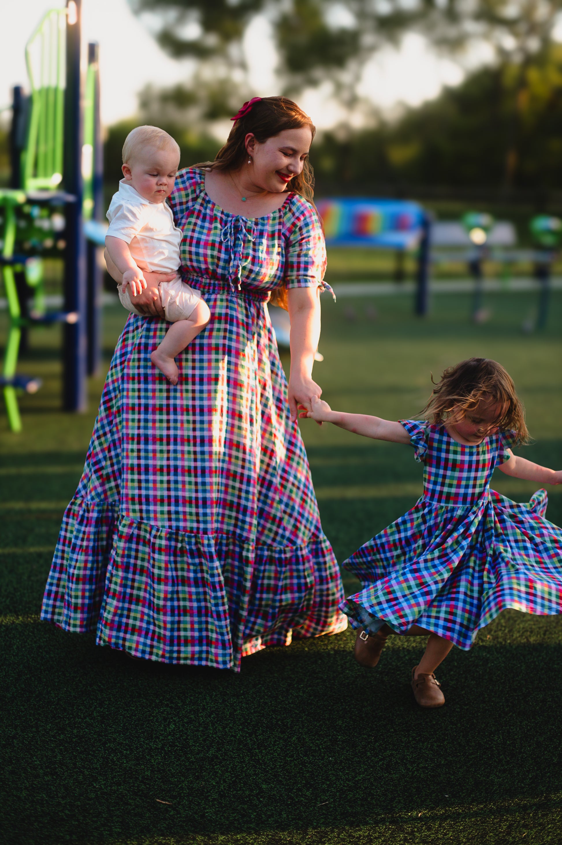 Young girl in a colorful checkered modest dress with her mother in a colorful modest nursing dress
