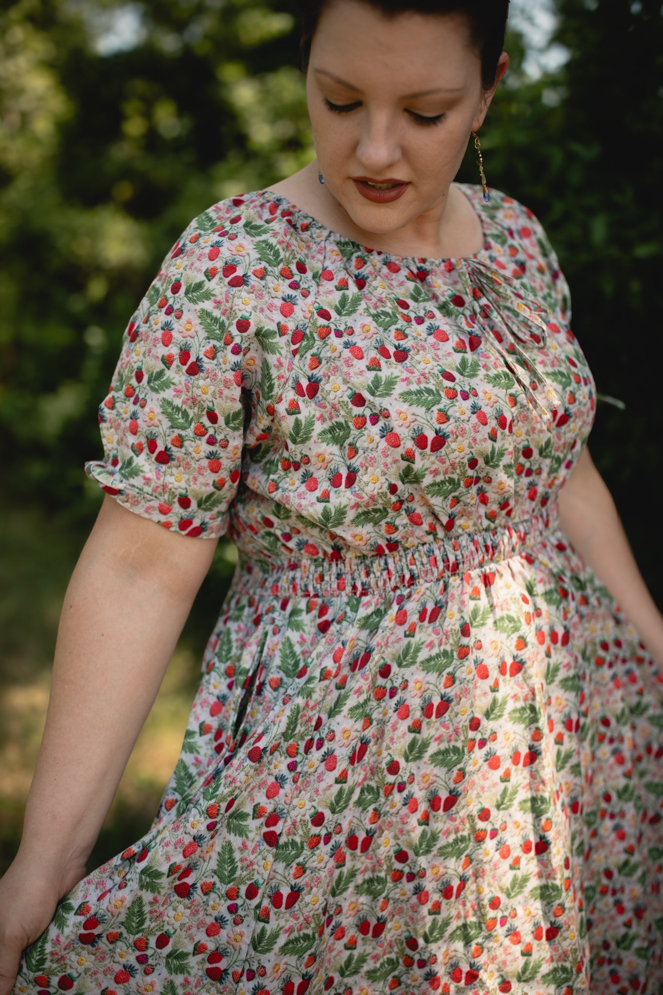 Woman wearing a floral modest nursing dress outdoors with greenery in the background