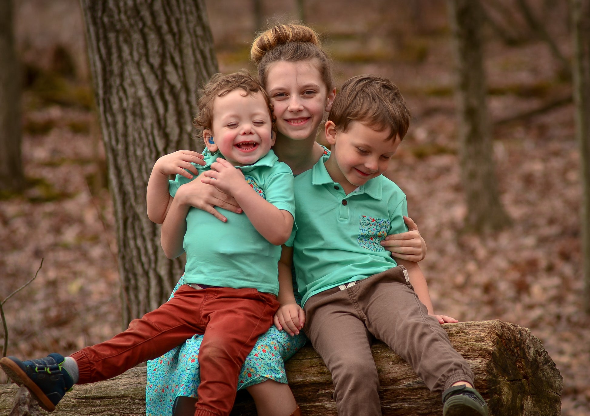 Young girl wearing a modest green dress with her brothers