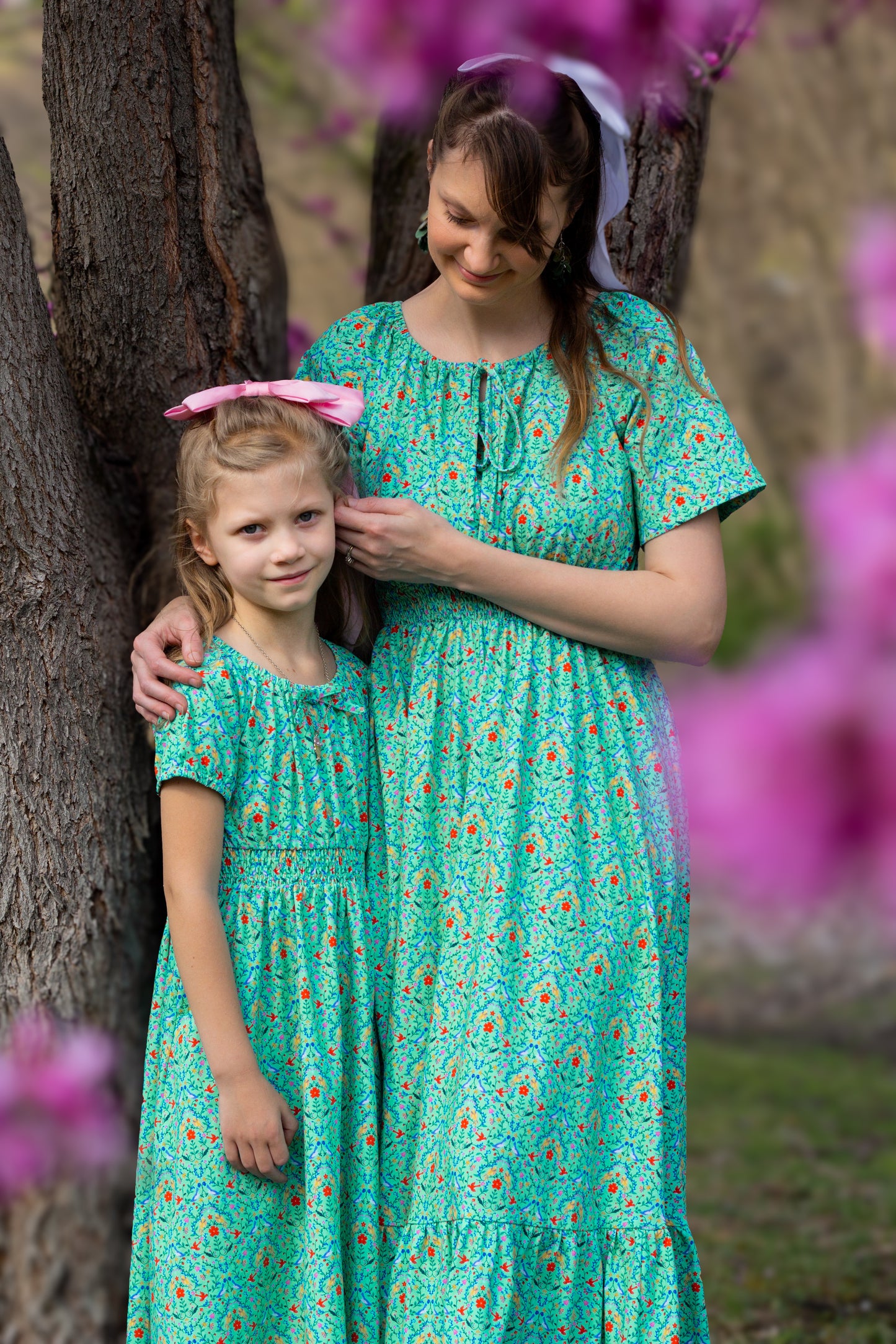 Young girl wearing a modest green dress with her mother in a modest green nursing dress