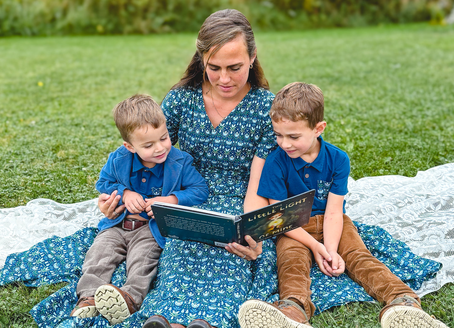 Mother in modest nursing dress reading to children outdoors