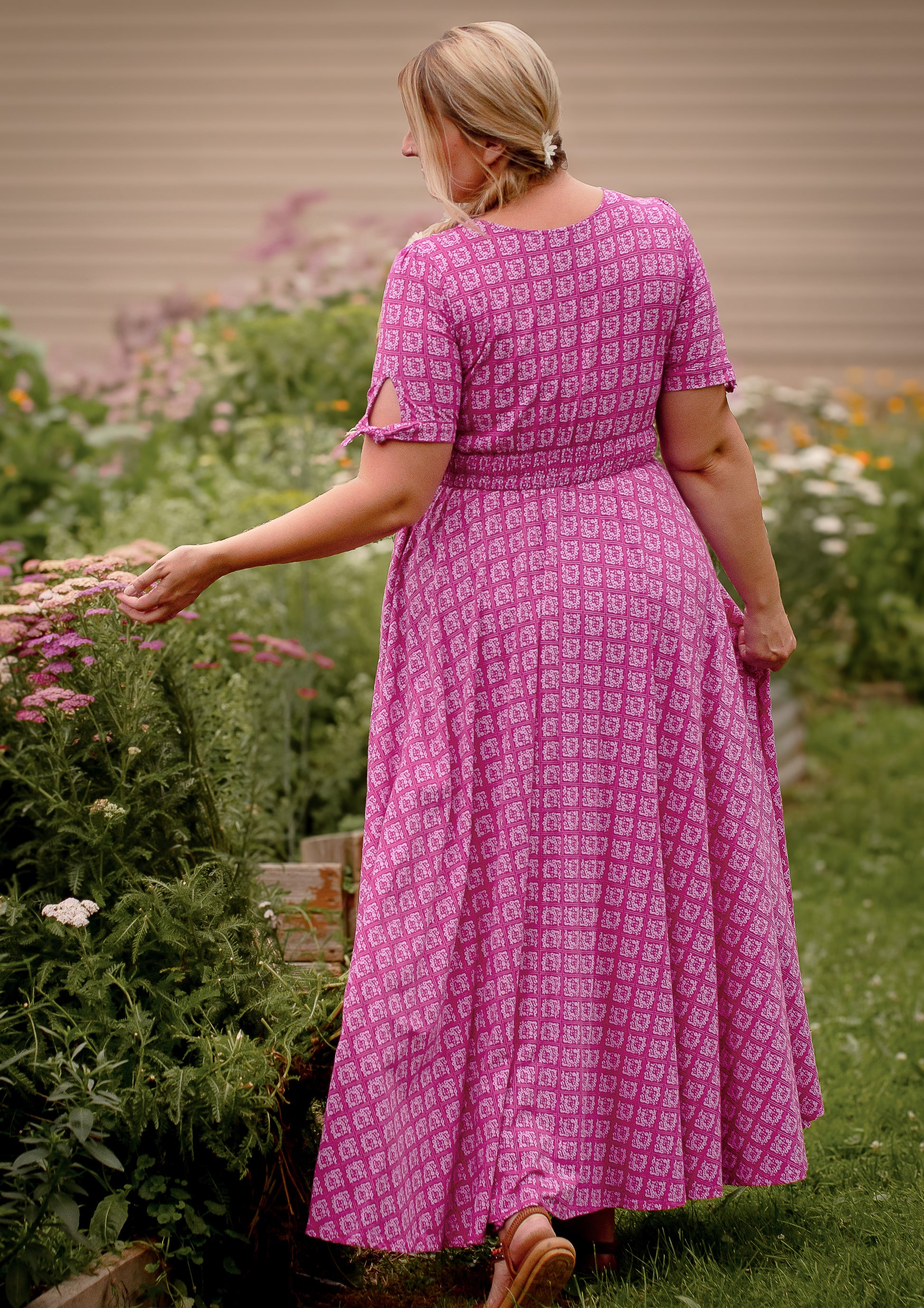 Woman in a pink modest nursing dress standing in a garden