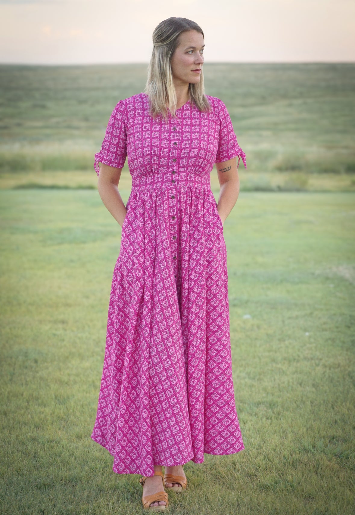 Woman in a pink modest nursing dress standing in a grassy field