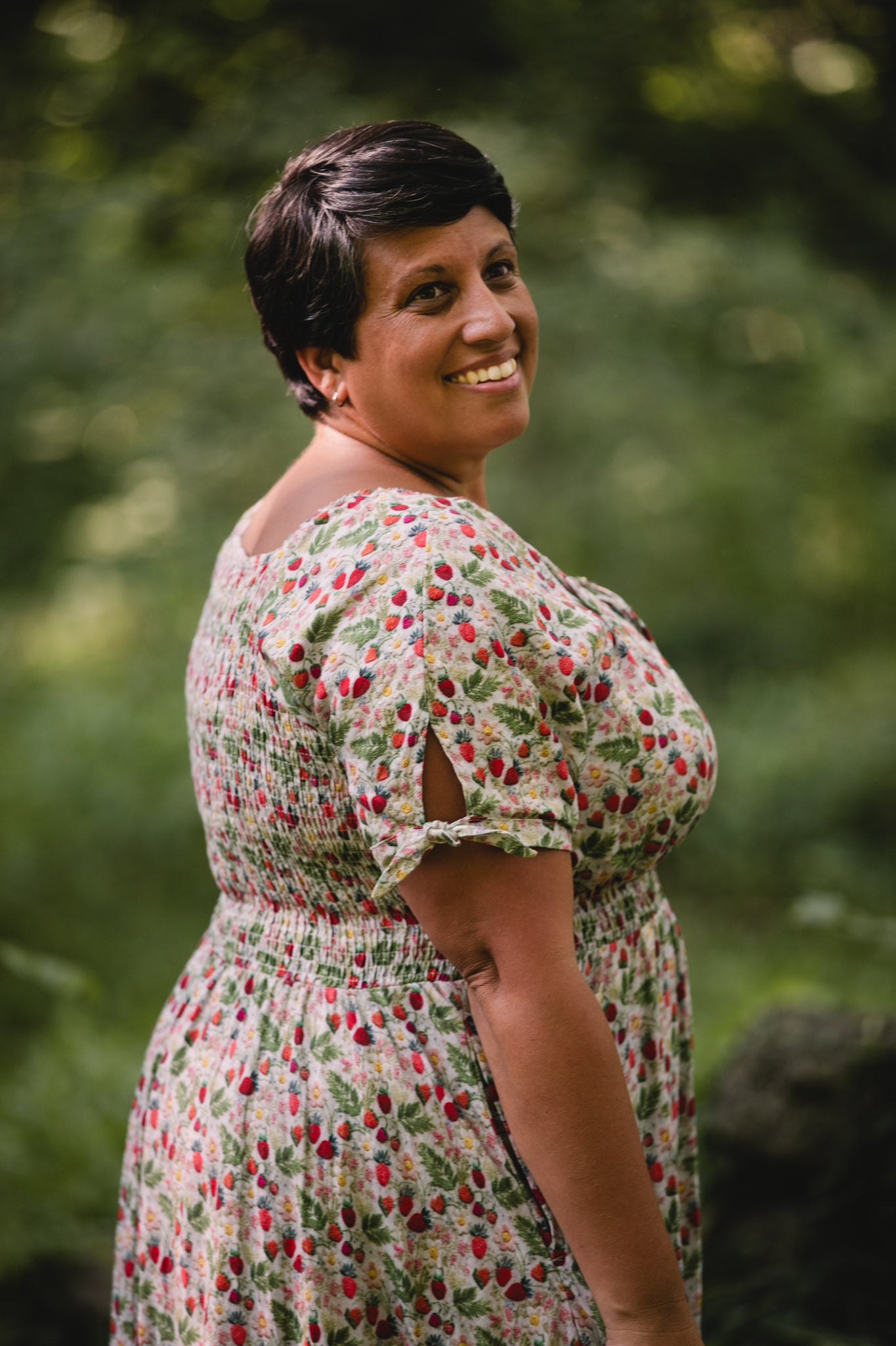 Woman wearing a floral modest nursing dress standing outdoors with greenery in the background