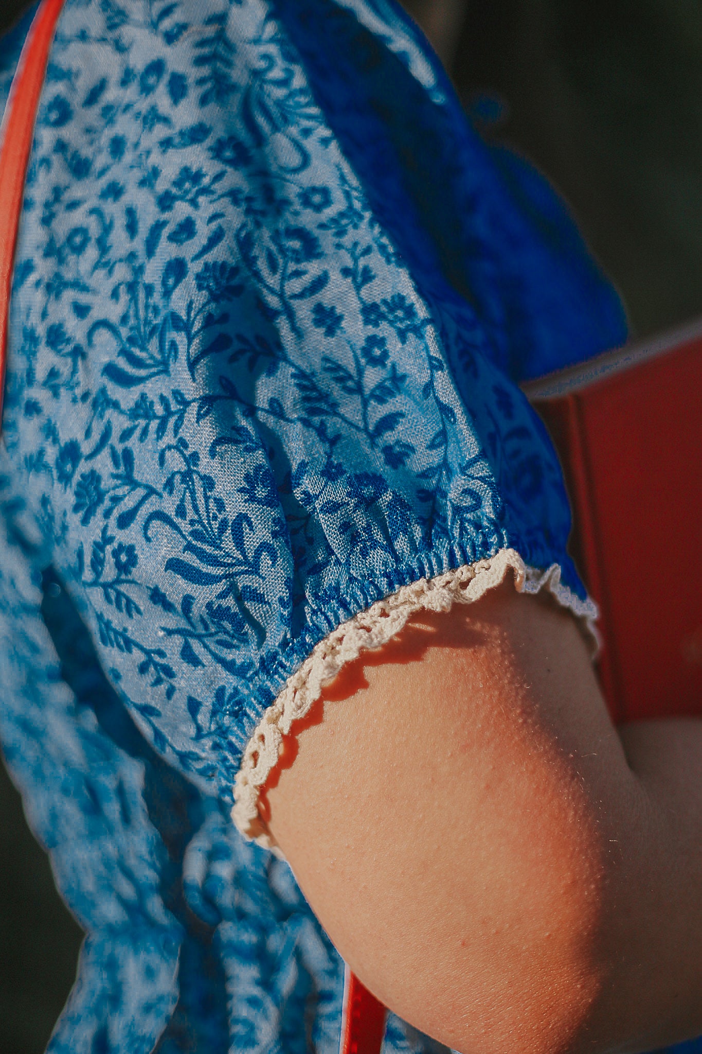 Close-up of a blue floral-patterned dress with lace trim.
