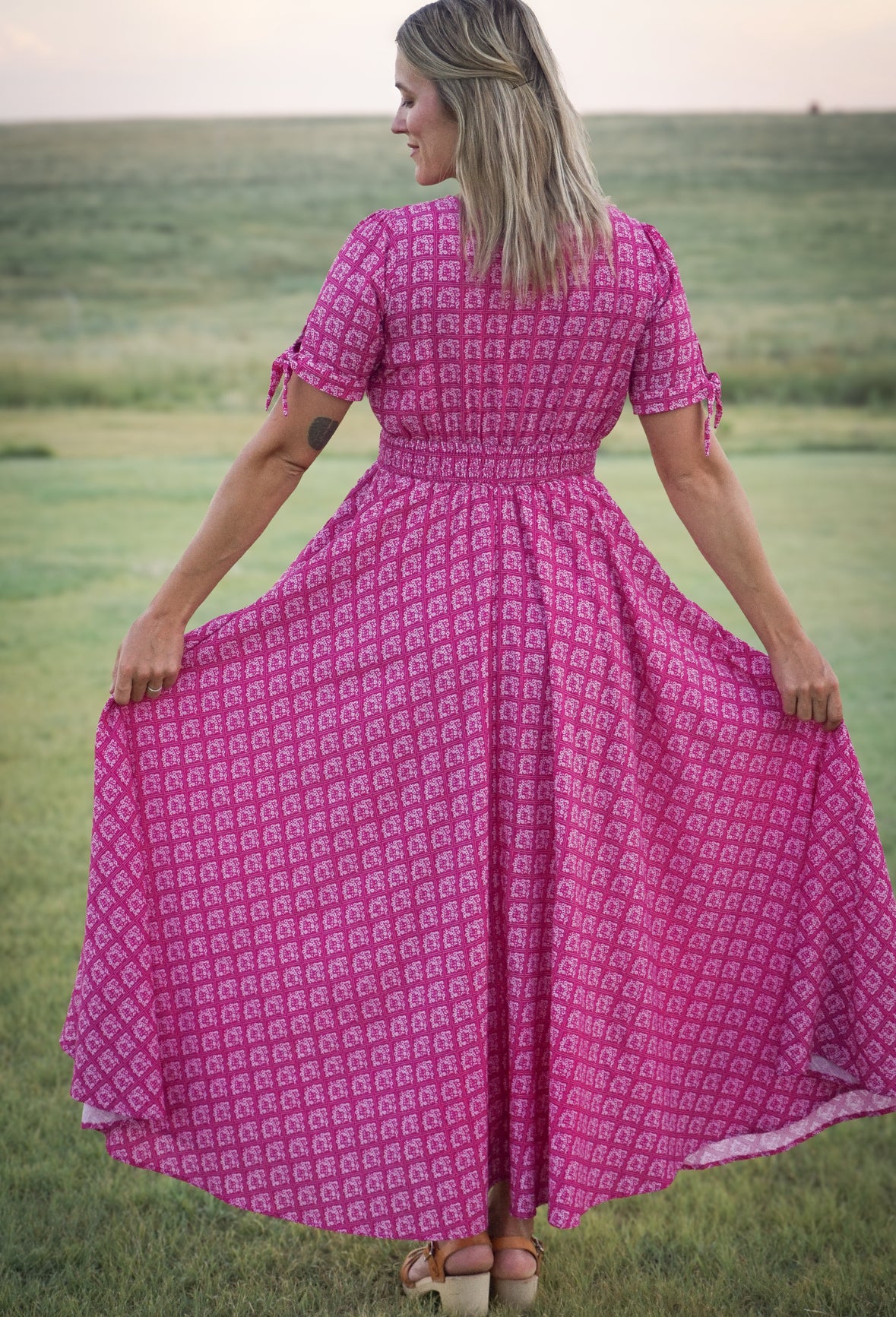 Woman in a pink modest nursing dress standing in a field