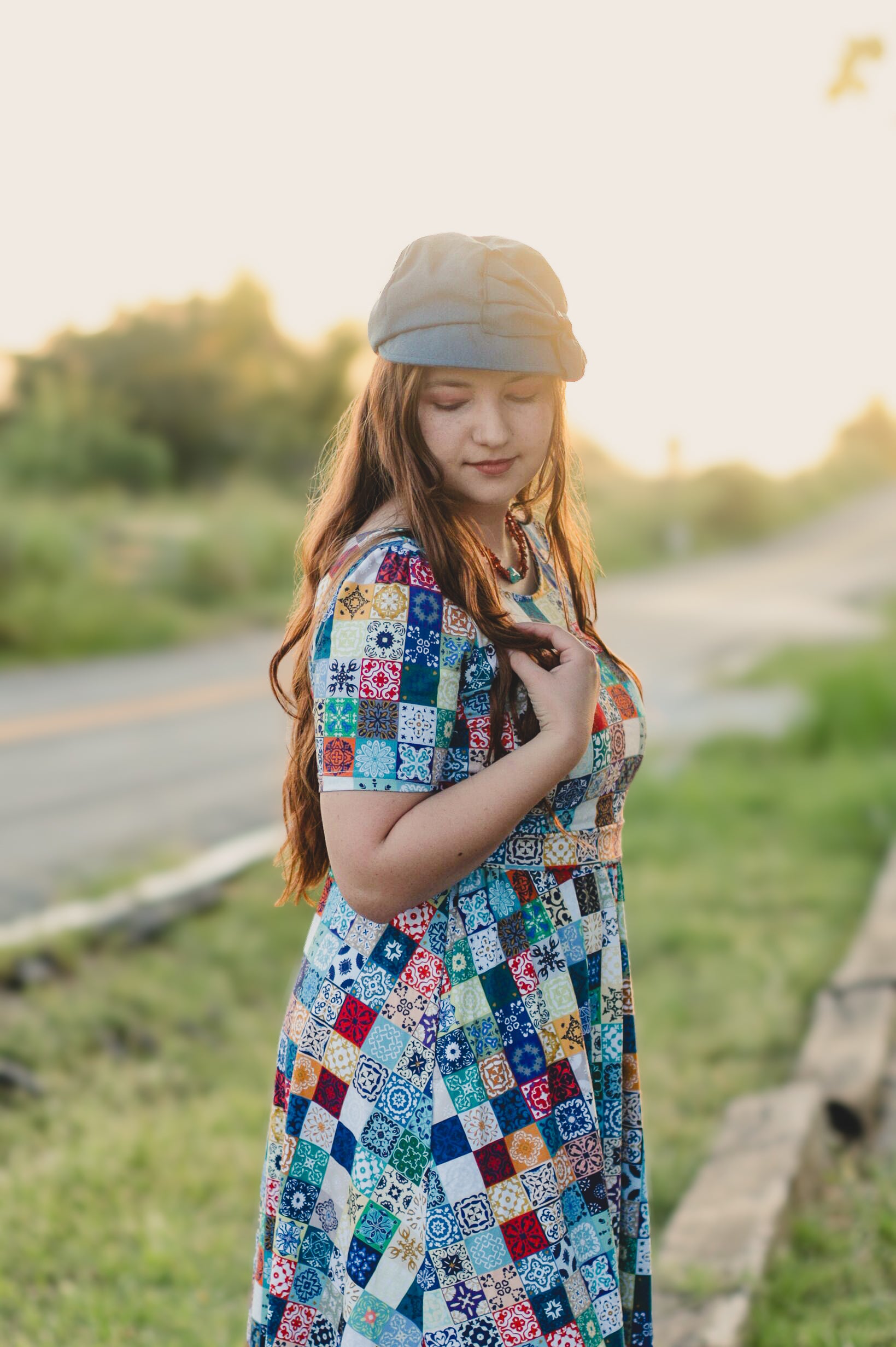 Young girl in a colorful patchwork modest nursing dress standing outdoors with a blurred background