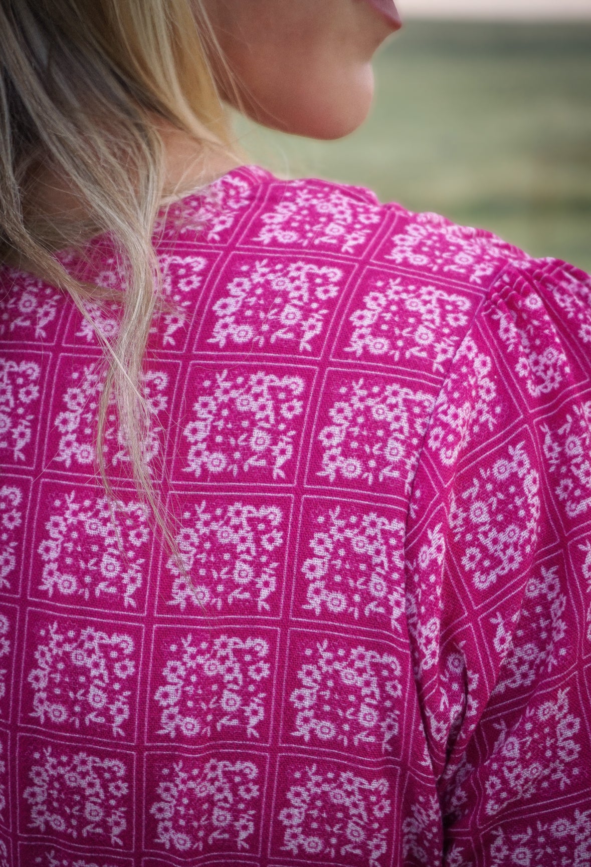 Close-up of a person wearing a pink patterned modest nursing dress with a blurred background