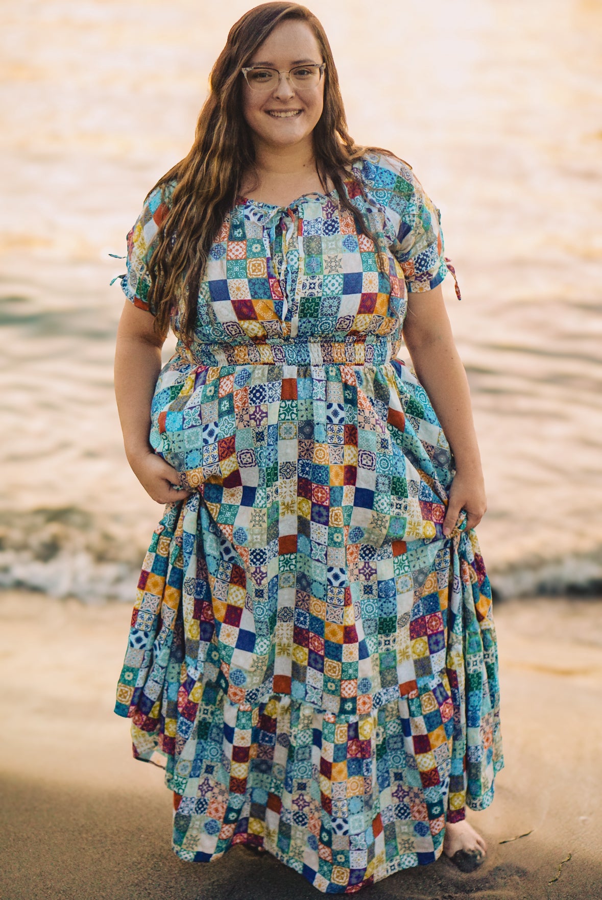 Woman wearing a colorful patterned modest nursing dress standing by a body of water.