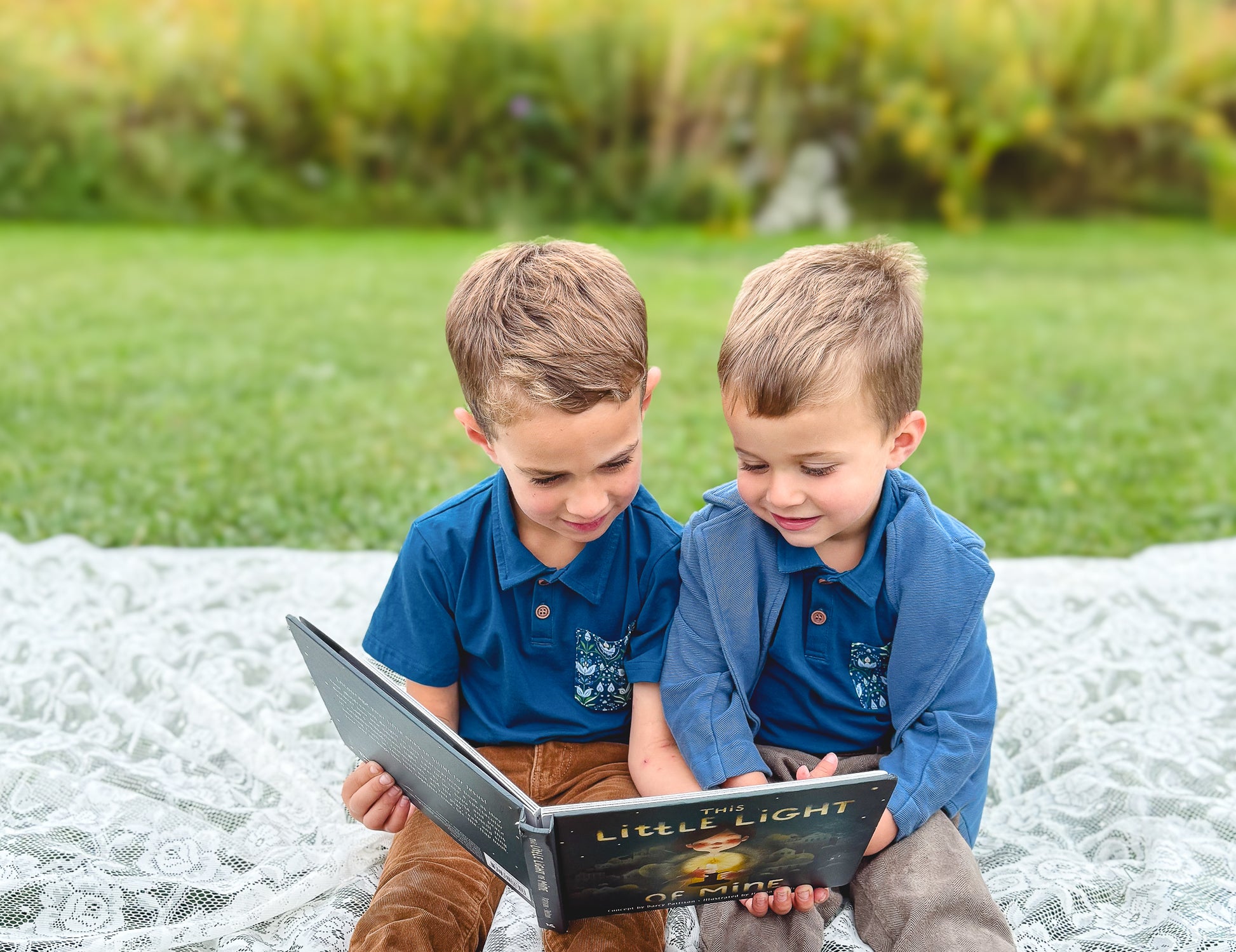 Two boys reading book outdoors in matching polos