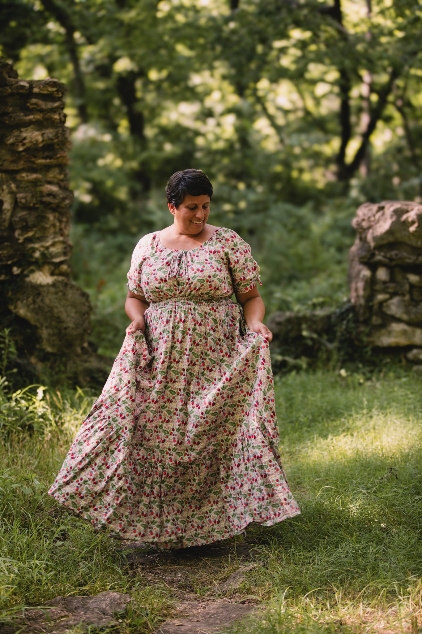 Woman in a floral modest nursing dress standing in a natural setting with greenery.