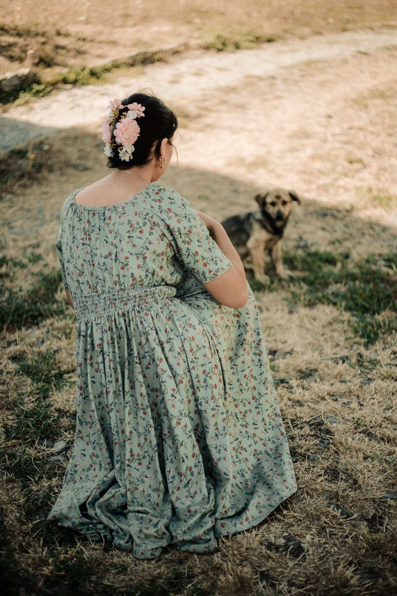 Woman in modest nursing floral dress with dog in field
