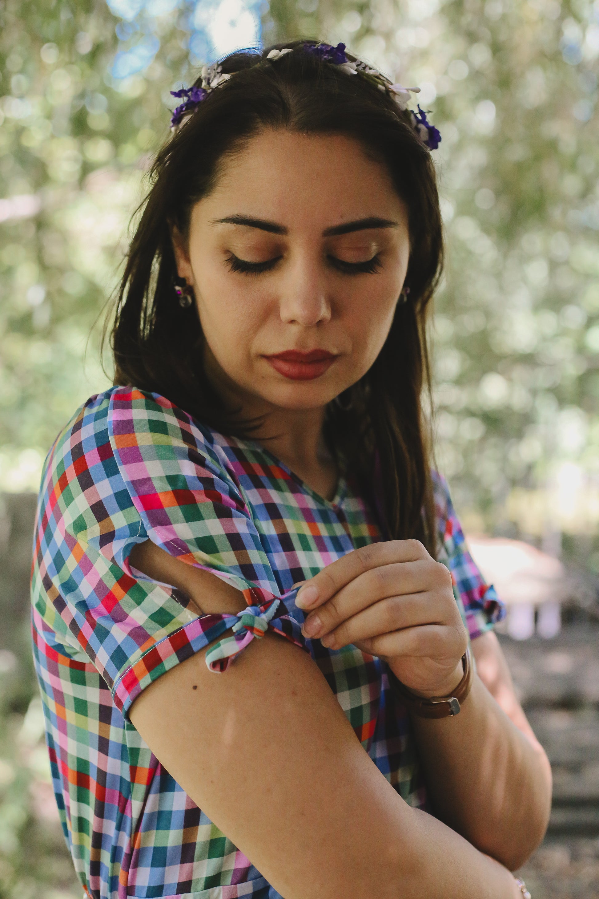 Woman wearing a colorful checkered modest nursing dress with a blurred natural background
