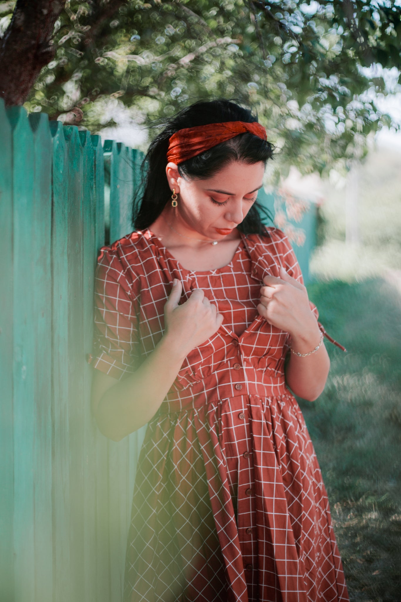 Woman in modest nursing red checkered dress fence