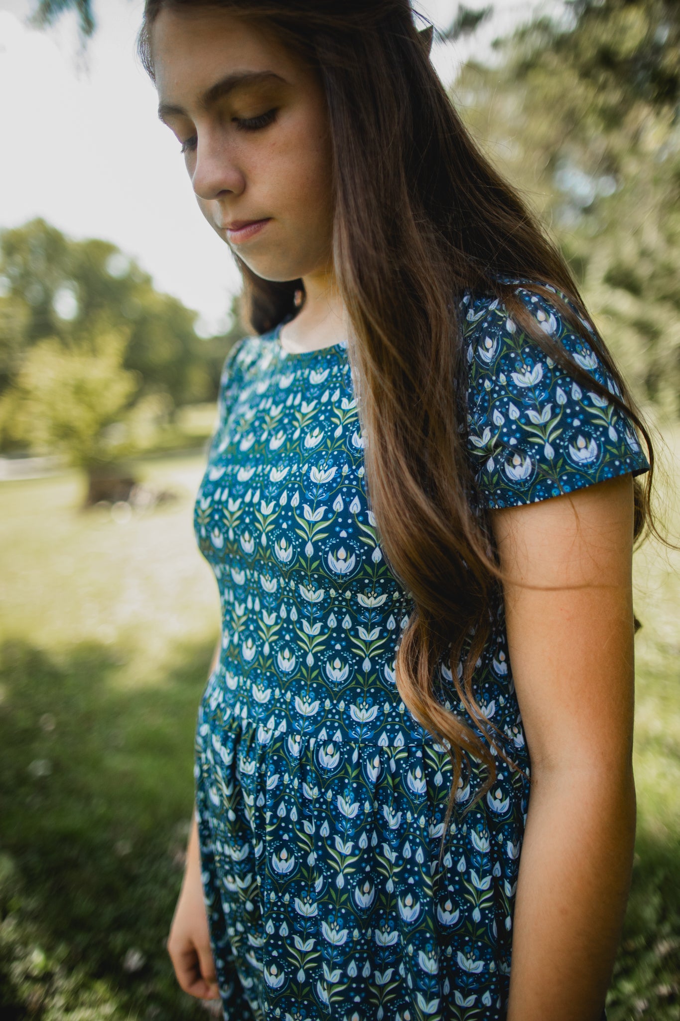 Woman in modest nursing dress outdoors with greenery