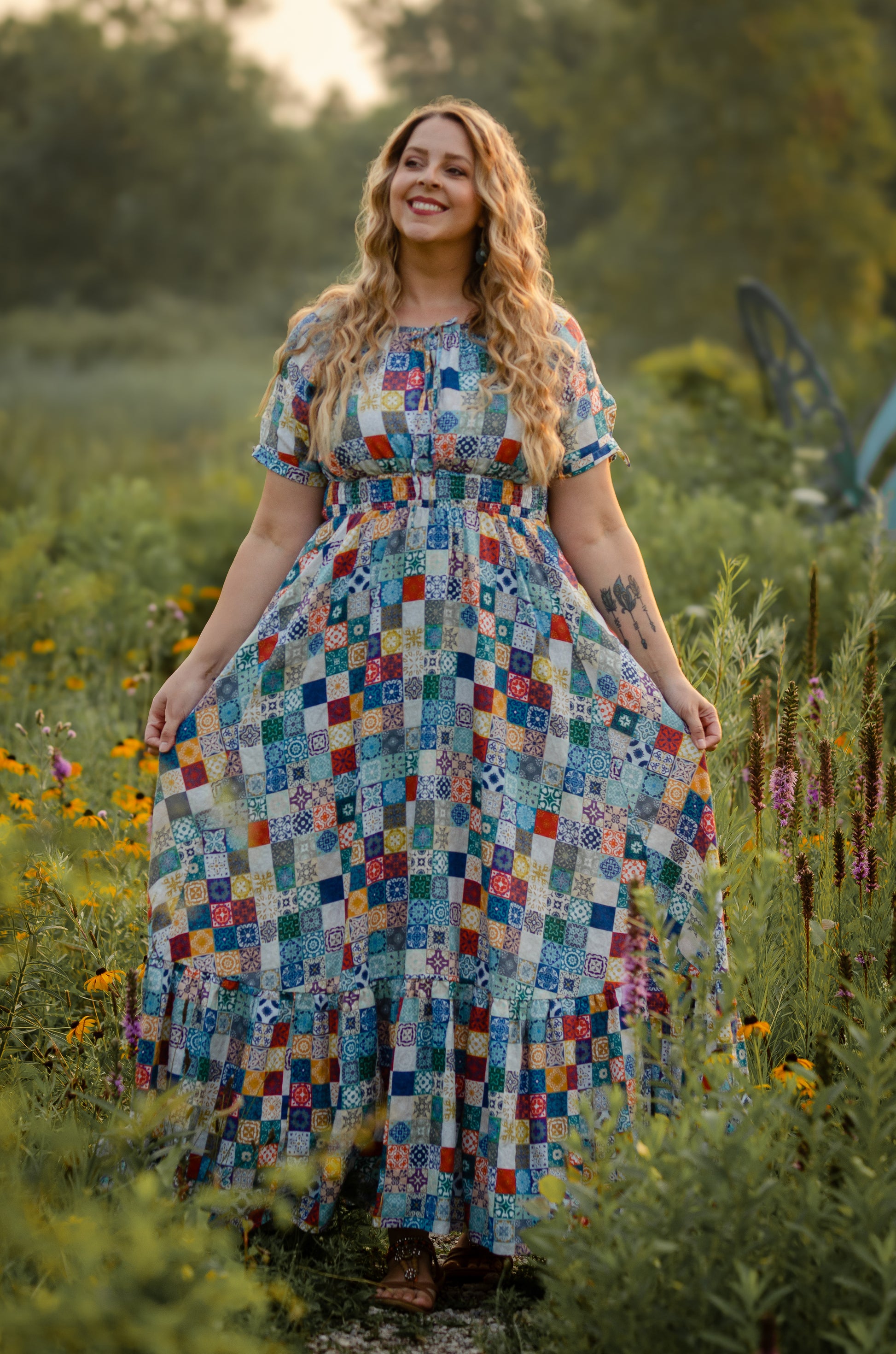 Woman in a colorful modest nursing dress standing in a field with flowers