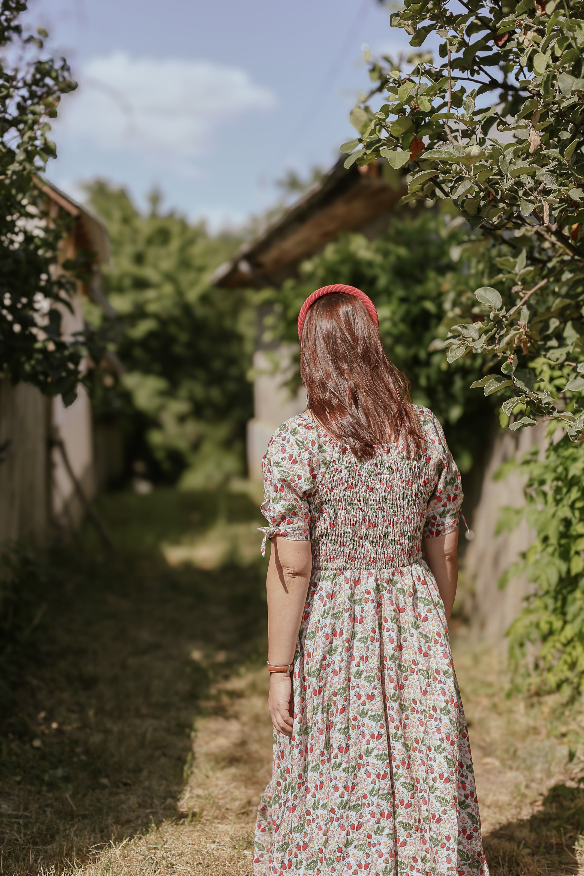 Woman in a floral modest nursing dress standing in an orchard