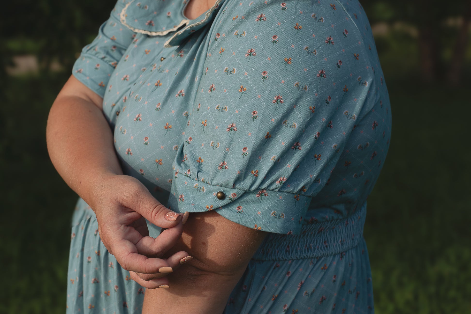 Person wearing a blue floral modest nursing dress with blurred background
